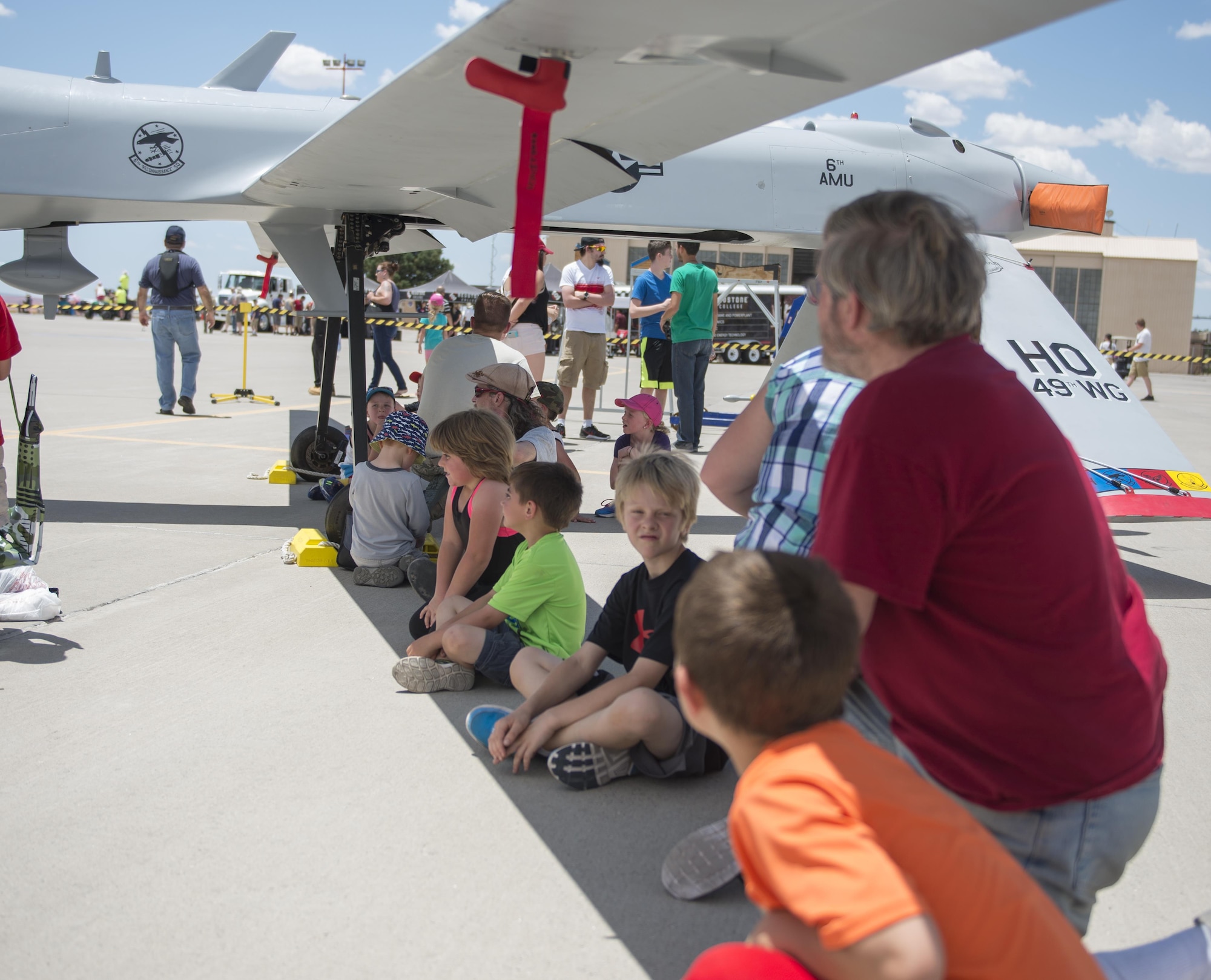 Visitors at the Kirtland Air Force Base Air Show rest in the shade of an MQ-1 Predator on June 5. Over 50,000 people visited the Kirtland AFB Open House June 4 and 5. Holloman Airmen had the opportunity to display an MQ-1 Predator and answer questions visitors had about RPAs and their mission at Holloman. (U.S. Air Force photo by Airman 1st Class Randahl J. Jenson) 