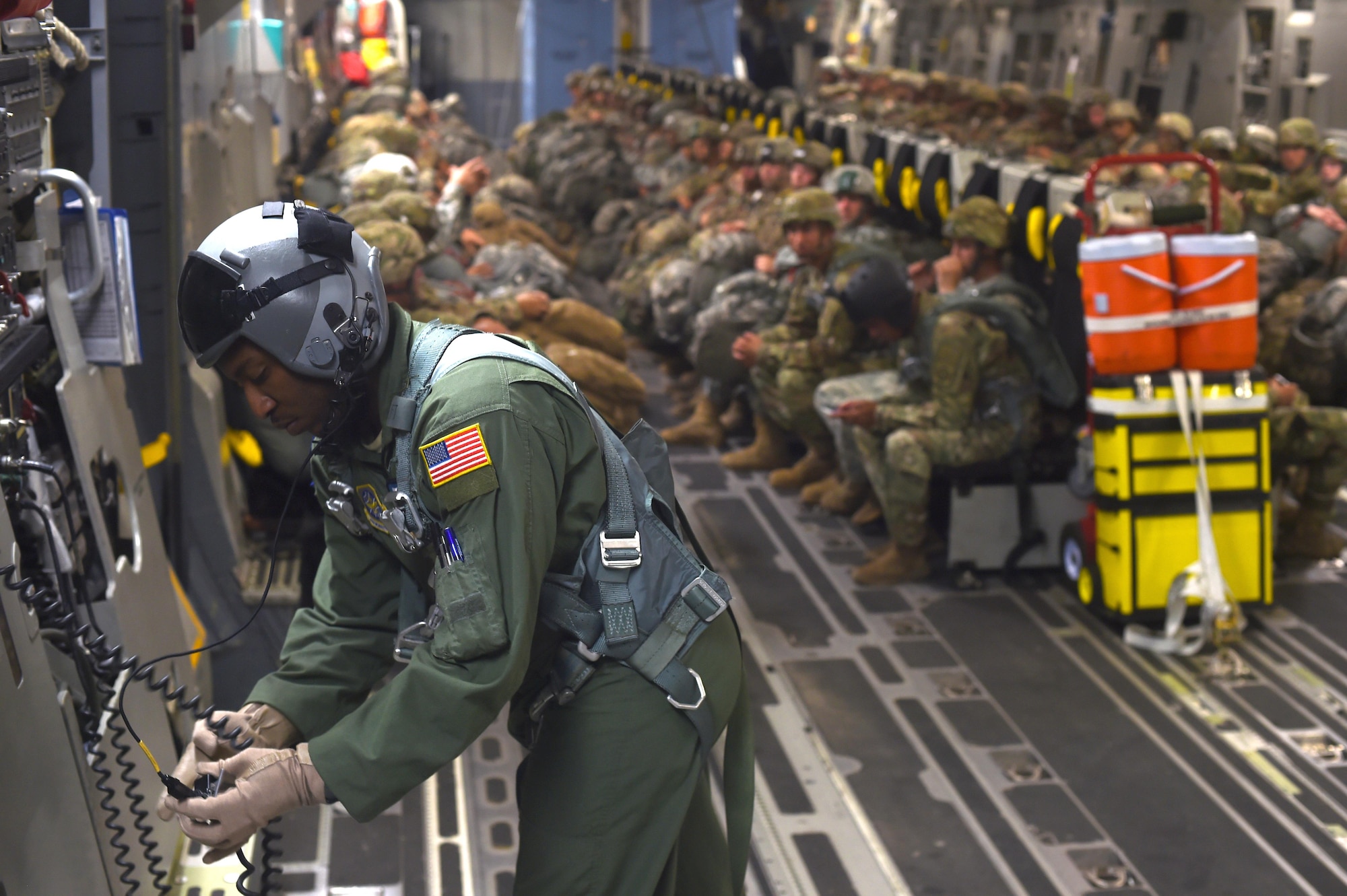 Staff Sgt. Seth Lewis, 7th Airlift Squadron C-17 loadmaster, conducts a communications check during an air drop over the Pope Army Air Field Range, North Carolina, June 4, 2016. Loadmasters are responsible for loading, securing and escorting cargo and passengers as well as calculating weight distribution. (U.S. Air Force photo/Staff Sgt. Naomi Shipley)