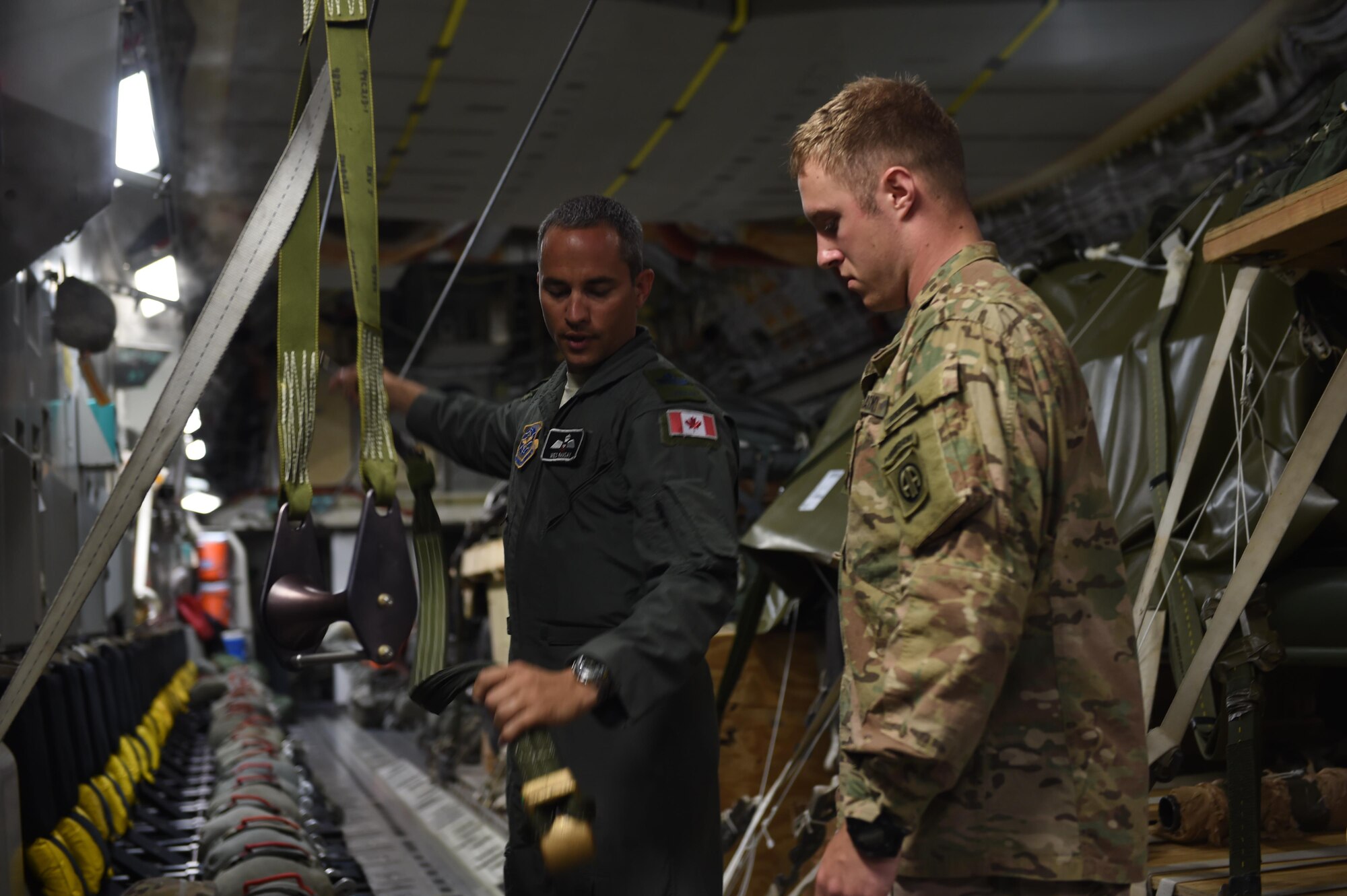 Royal Canadian Air Force Sgt. Wes Ramsay, 8th Airlift Squadron C-17 Globemaster III loadmaster instructs Army Capt. Justin Schumaker, Headquarters and Headquarters Company, 1st Brigade, 82nd Airborne Division, on the rigging set up inside a C-17 at Pope Army Air Field, N.C., on June 6, 2016. Three 62nd Airlift Wing C-17’s flew to Poland to conduct equipment and personnel air drops in support of Exercise Swift Response 2016. (Air Force photo/Staff Sgt. Naomi Shipley)
 
