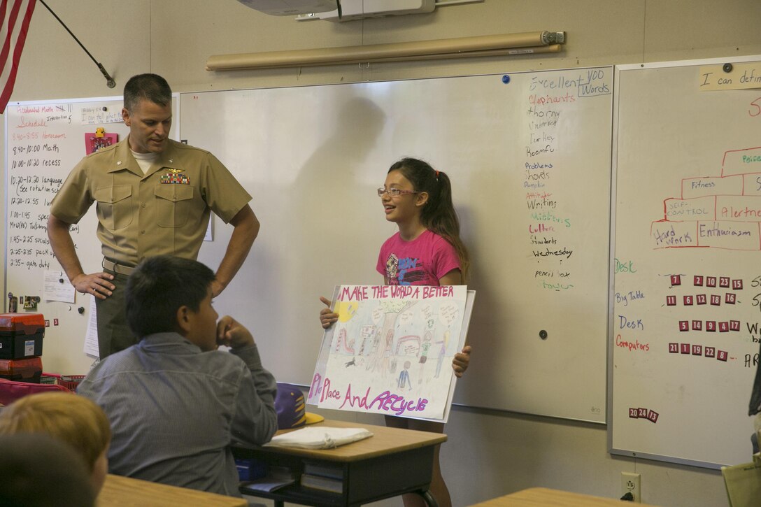 Lt. Col. Timothy Pochop, director, Natural Resources and Environmental Affairs, congratulates Nicole Doten, fifth Grader, for being one of the finalists of the 2016 Earth Day Poster Contest at Twentynine Palms Elementary School June 2, 2016. (Official Marine Corps photo by Cpl. Thomas Mudd/Released)
