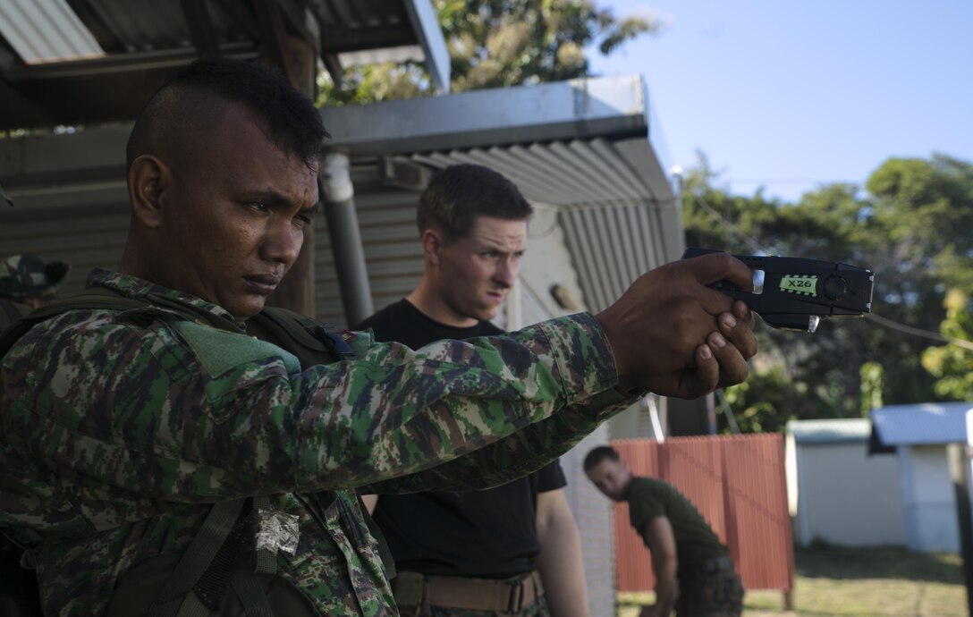Pvt. Oldegar Gusmao (Left) fires an X26-E Taser under the instruction of Cpl. Preston G. Thompson (Right) during a non-lethal weapons course, June 7, 2016, at Metinaro, Timor Leste, as part of Exercise Crocodilo 16. The course gives Marines an opportunity to instruct Timorese soldiers on less-than-lethal methods for handling any disputes in the future. Crocodilo is a multi-national, bilateral exercise designed to increase interoperability and relations by sharing infantry, engineering, combat lifesaving and law enforcement skills. Gusmao an infantryman with Bravo Company, 1st Battalion, Timor Leste Defense Force, stationed in Baucau, Timor Leste. Thompson, from Wyoming, Michigan, is a military policeman and chief instructor for the non-lethal weapons course with Task Force Koa Moana, originally assigned to Charlie Company, 3rd Law Enforcement Battalion, III Marine Expeditionary Force.