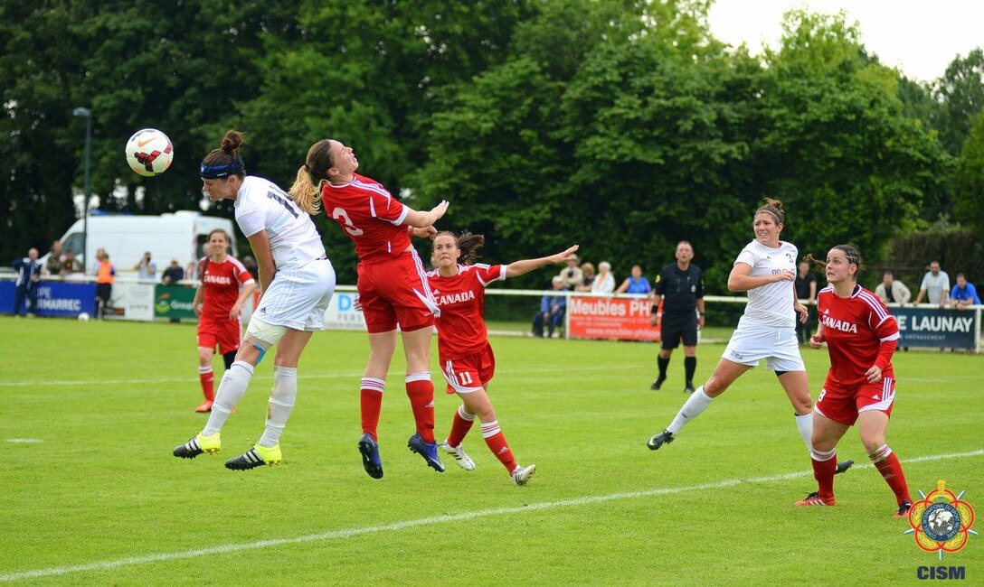 Navy Lt. Michelle Moeller (#14 left-heading the ball) and Marine Kate Herren (#3 right) both scored against Canada to win the match 4-3.  France hosted the 2016 Conseil International du Sport Militaire (CISM) World Football Cup in Rennes, France from 24 May to 5 June.  USA finished 7th overall as host nation France won the Cup.
