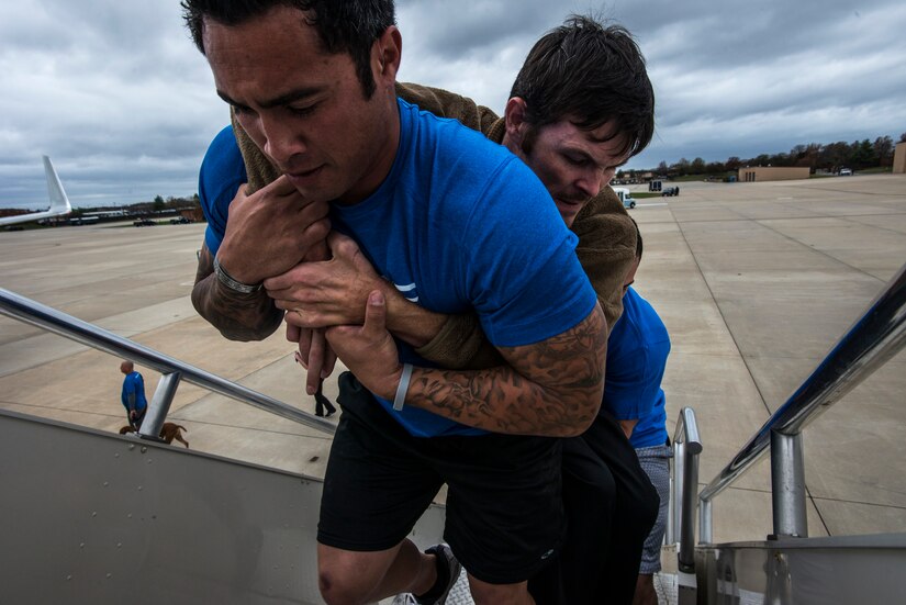 Tech. Sgt. Christopher Ferrell, 11th Civil Engineer Squadron explosive ordnance disposal technician, carries 1st Lt. Nathan Nelson (Ret.) up a flight of stars so they can tour an 89th Airlift Wing C-32A at Joint Base Andrews, Md., Nov. 15, 2015. Ferrell is an Air Force Wounded Warrior and will compete at the Department of Defense 2016 Warrior Games June 16-21, 2016. (U.S. Air Force photo by Senior Master Sgt. Kevin Wallace)