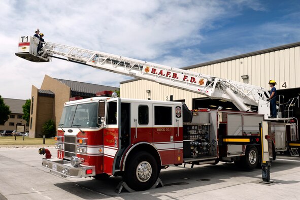 Joshua Jones, top left, gets a lift in a ladder fire truck June 9 at Fire Station #1, Hill Air Force Base, Utah. Jones, who has a life-threatening illness, has always loved fire trucks and firefighters. While here, he and his family toured a fire station, rode in a fire truck, and participated in firefighting training with firefighters from the 419th Fighter Wing. (U.S. Air Force photo by Todd Cromar) 
