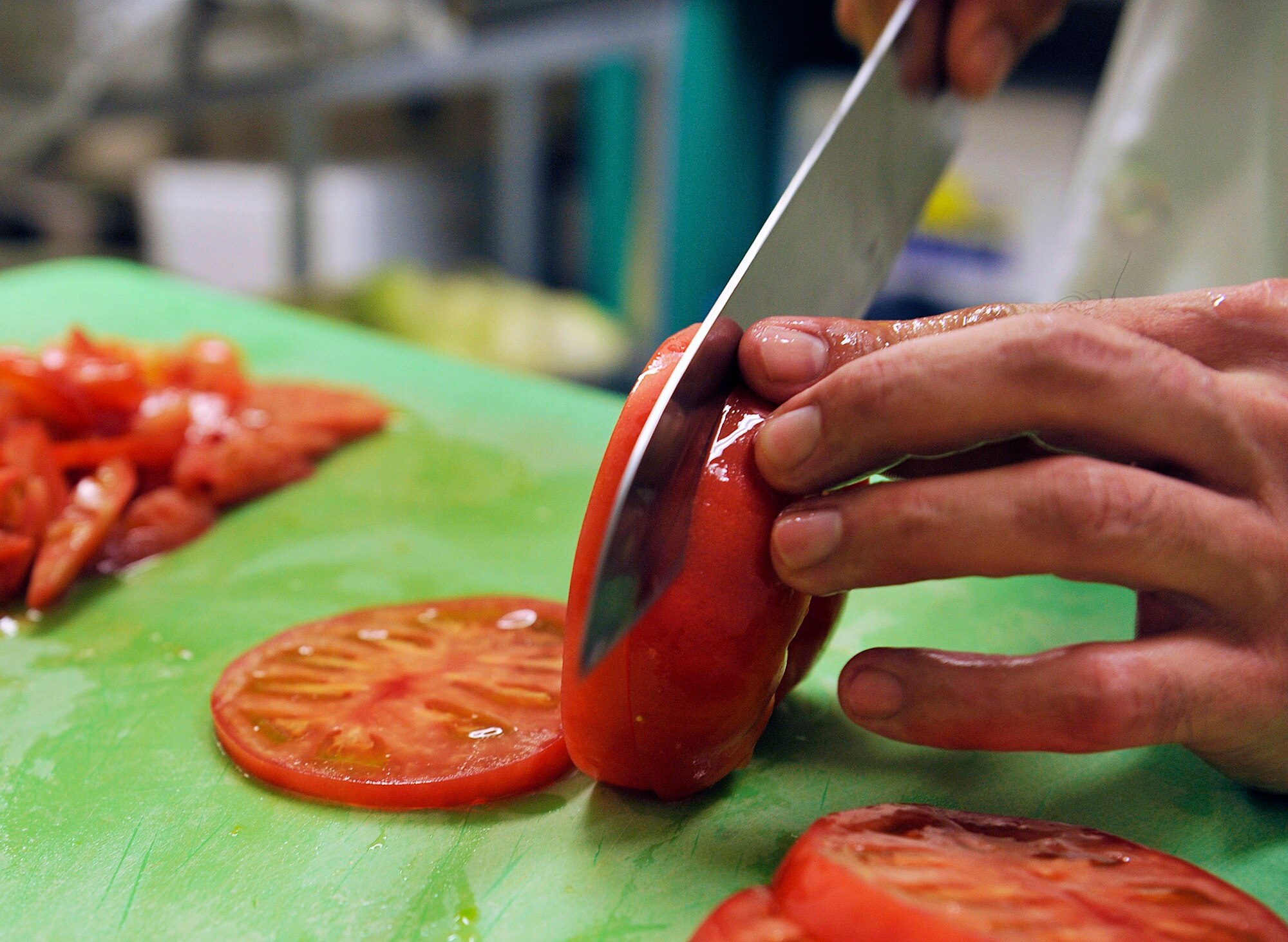 Takashi Seragaki, 18th Force Support Squadron cook, cuts tomatoes during lunch at the Marshall Dining Facility, June 3, 2016, at Kadena Air Base, Japan. Seragaki has felt welcomed by the Marshall DFAC team since his first day at work. (U.S. Air Force photo by Naoto Anazawa)

