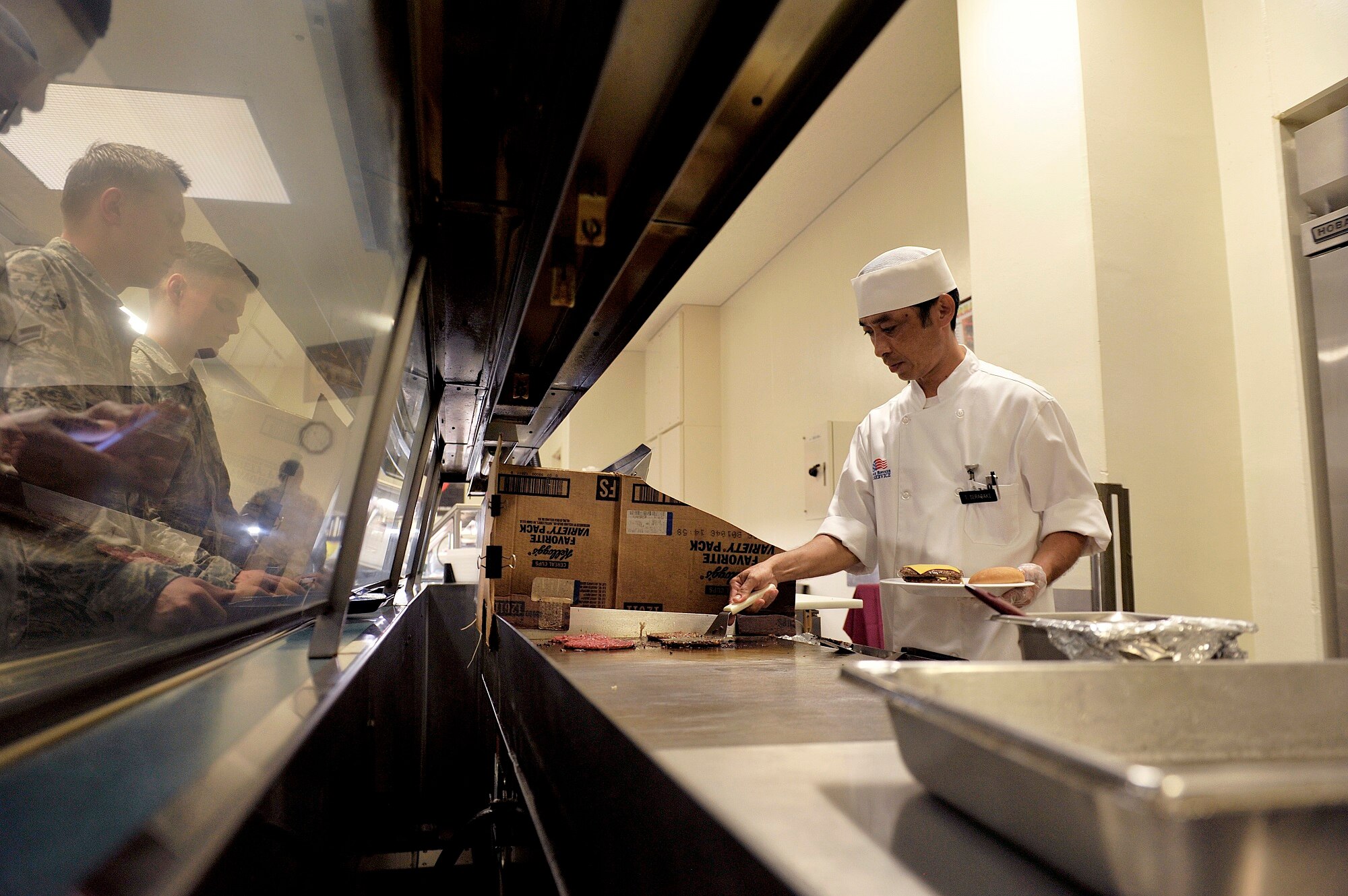 Takashi Seragaki, 18th Force Support Squadron cook, prepares food for Airmen at the Marshall Dining Facility, June 3, 2016, at Kadena Air Base, Japan. The facility serves breakfast, lunch, dinner, a la carte menus and midnight meals for Airmen to help them stay mission ready. (U.S. Air Force photo by Naoto Anazawa)