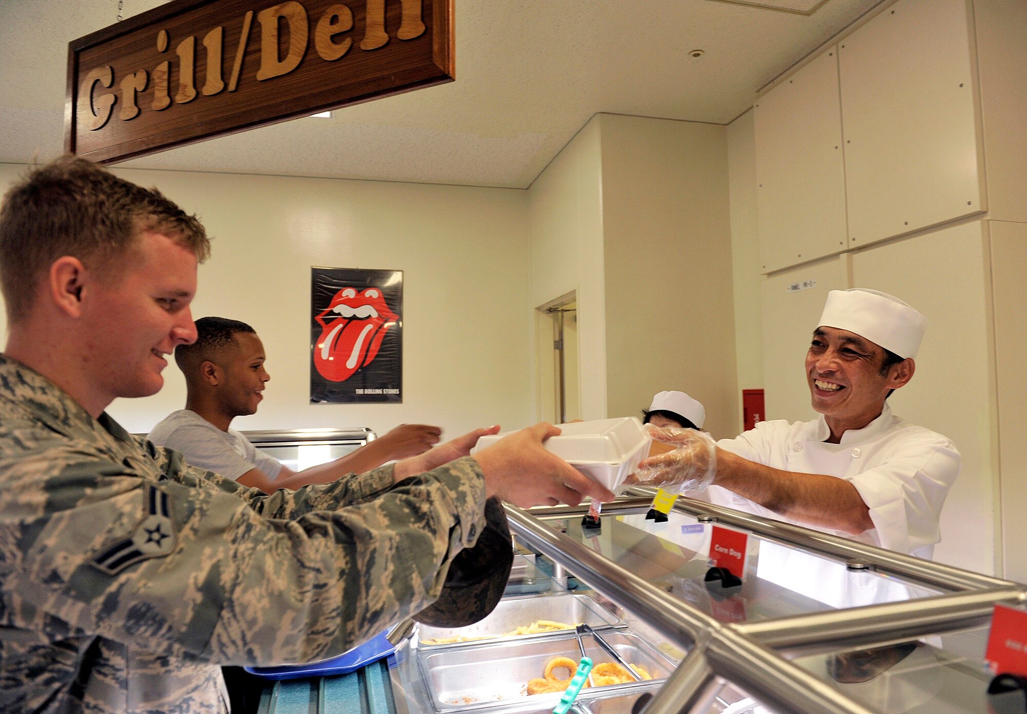 Takashi Seragaki, 18th Force Support Squadron cook, serves a meal to an Airman at the Marshall Dining Facility, June 3, 2016, at Kadena Air Base, Japan. Seragaki said he feels satisfied when he sees customers enjoying the meals he worked hard to make. (U.S. Air Force photo by Naoto Anazawa)