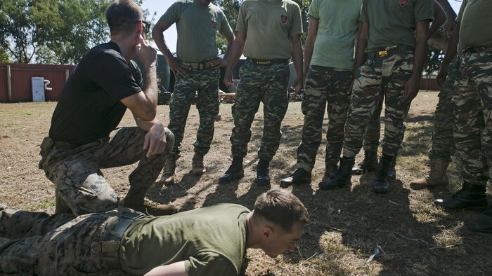Cpl. Zachary A. Barnett (Left) demonstrates pressure point techniques with Lance Cpl. Christopher M. Hettinger (Bottom) during a non-lethal weapons course with Timorese soldiers, June 7, 2016, at Metinaro, Timor Leste, as part of Exercise Crocodilo 16. The non-lethal weapons course gives Marines the opportunity to share techniques with the host nation to give their nation a better means to handle future disputes. Crocodilo is a multi-national, bilateral exercise designed to increase interoperability and relations by sharing infantry, engineering, law enforcement and combat lifesaving skills. Barnett is a non-lethal weapons instructor with Task Force Koa Moana.  Barnett, from Yuba City, California, and Hettinger, from Strawberry Point, Iowa, are military policeman with the task force, originally assigned to Bravo Company, 3rd Law Enforcement Battalion, III Marine Expeditionary Force.
