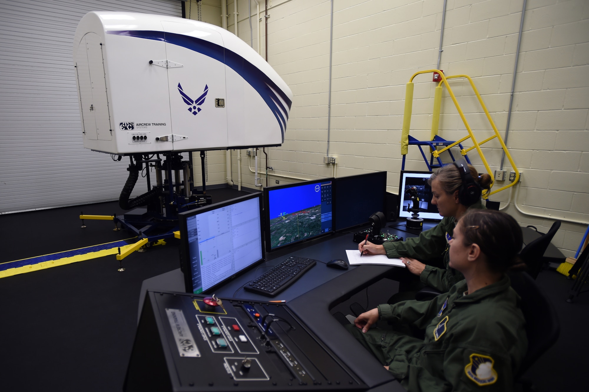 Tech. Sgt. Dannella Smith, 359th Aerospace Medicine Squadron aerospace and operational physiology technician, and Maj. Jennifer Giovannetti, 359th AMDS Aerospace and Physiology Flight commander, perform preflight checks before setting up a spatial disorientation illusion profile June 7 at Joint Base San Antonio – Randolph. The trainer helps pilots correctly identify the different types of air sickness they may encounter during flight. (U.S. Air Force photo/Staff Sgt. Jason Huddleston/Released)