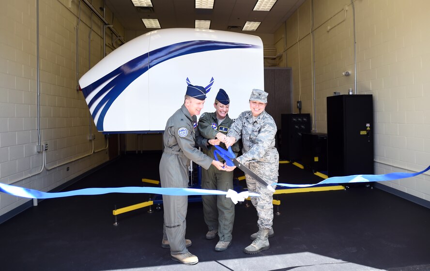 Brig. Gen. John A. Cherrey, Air Education and Training Command director of intelligence, operations and nuclear integration; Maj. Jennifer Giovannetti, 359th Aerospace Medicine Squadron Aerospace and Physiology Flight commander; and Col. Dana James, 359th Medical Group commander, cut the ribbon in front of the GYRO Integrated Physiological Trainer II during a June 7 ceremony at Joint Base San Antonio – Randolph. The $1 million flight trainer prepares pilots to recognize, confirm, prevent and recover from spatial disorientation before they fly for the first time. (U.S. Air Force photo/Staff Sgt. Jason Huddleston/Released)