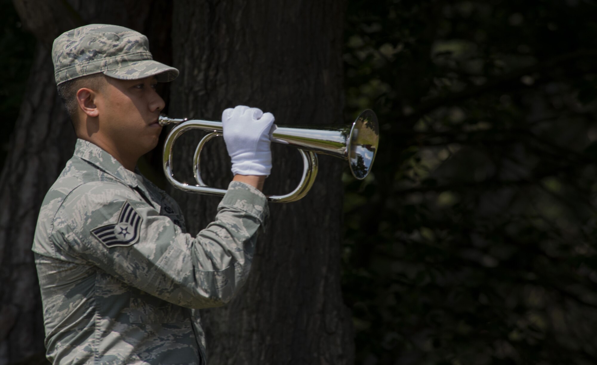 Staff Sgt. Srun Sookmeewiriya, 313th Expeditionary Operations Support Squadron senior controller, plays Taps on the bugle during a funeral ceremony demonstration as part of the Air Education and Training Command’s Class 5 Basic Protocol, Honors and Ceremonies Course graduation ceremony June 9, 2016, at Ramstein Air Base, Germany. The graduates completed 80 hours of training in pallbearing, firing party, colors and maintenance and wear of the ceremonial uniform. The course emphasized the importance of military customs and courtesies, dress and appearance and drill and ceremony. (U.S. Air Force photo/Airman 1st Class Tryphena Mayhugh)