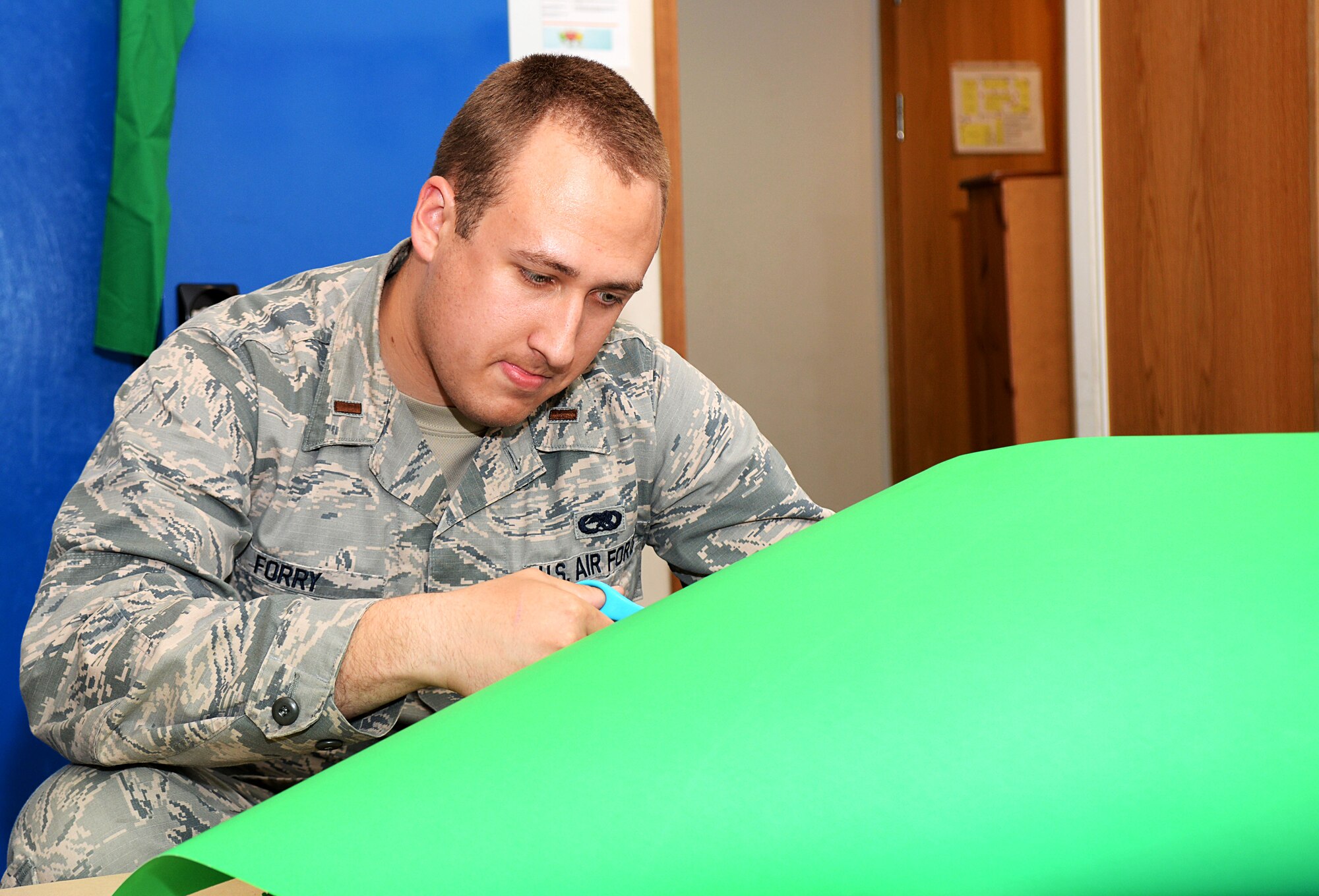 U.S. Air Force 2nd Lt. Kyle Forry, 352nd Special Operations Maintenance Squadron assistant aircraft maintenance unit officer in charge, cuts out crafts for the “Hearts Apart” event at the base chapel June 9, 2016, on RAF Mildenhall, England. “Hearts Apart” is a free dinner held monthly for the families of deployed service members. The crafts included personalized superhero capes and masks. (U.S. Air Force photo by Airman 1st Class Tenley Long/Released)