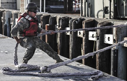 A Soldier assigned to 331st Modular Causeway Company, 11th Transportation Battalion, 7th Sustainment Brigade from Fort Eustis, Va., docks part of a modular causeway system during Joint Logistics Over the Shore at the Port of Tacoma, Wash., June 6, 2016. Sections of the Modular Causeway can be combined on a bare beach in order to supply emergency resources to areas affected by natural disaster.