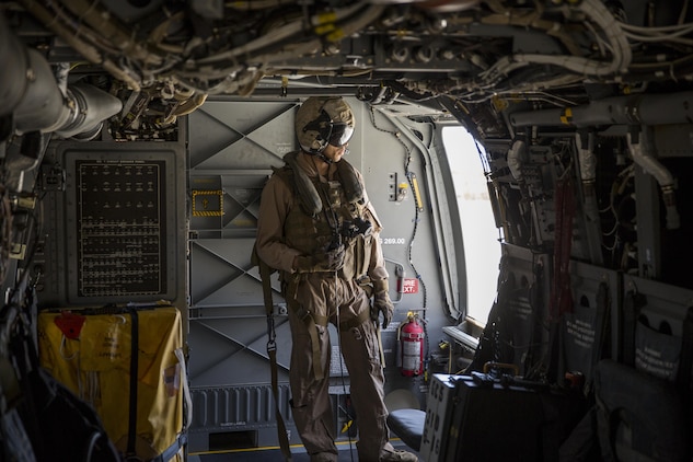 A crew chief with Marine Medium Tiltrotor Squadron (VMM) 165 looks outside an MV-22B Osprey during a training flight from Marine Corps Air Station Miramar to Marine Corps Base Camp Pendleton, Calif., June 8. Crew chiefs aboard the Osprey assisted with maintaining visuals during the flight for the pilots. (U.S. Marine Corps photo by Sgt. Michael Thorn/Released)