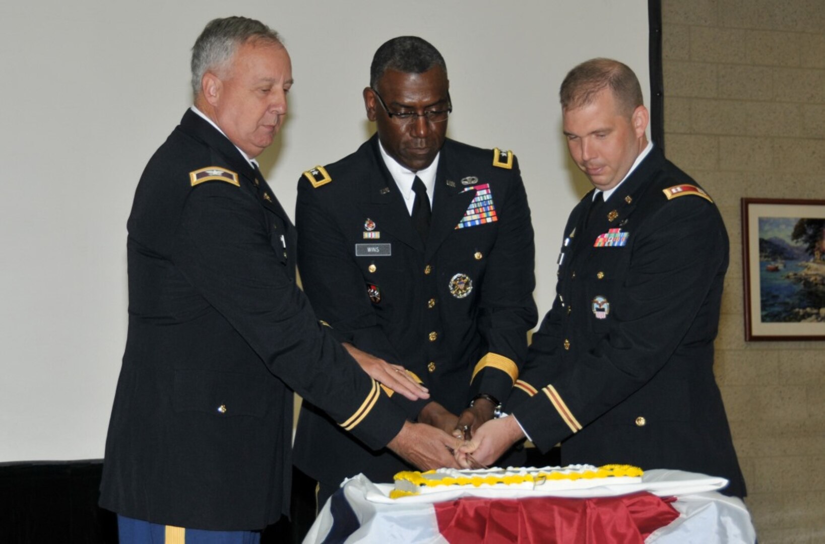Maj. Gen. Cedric T. Wins, center, director, Force Development Office of the Deputy Chief of Staff, is flanked by Col. Brad Hildabrand, left, and Capt. Zach Palko as they cut the cake at the 241st Army Birthday celebration at the McNamara Headquarters Complex June 9. Hildabrand was the oldest soldier at the ceremony, while Palko was the youngest.