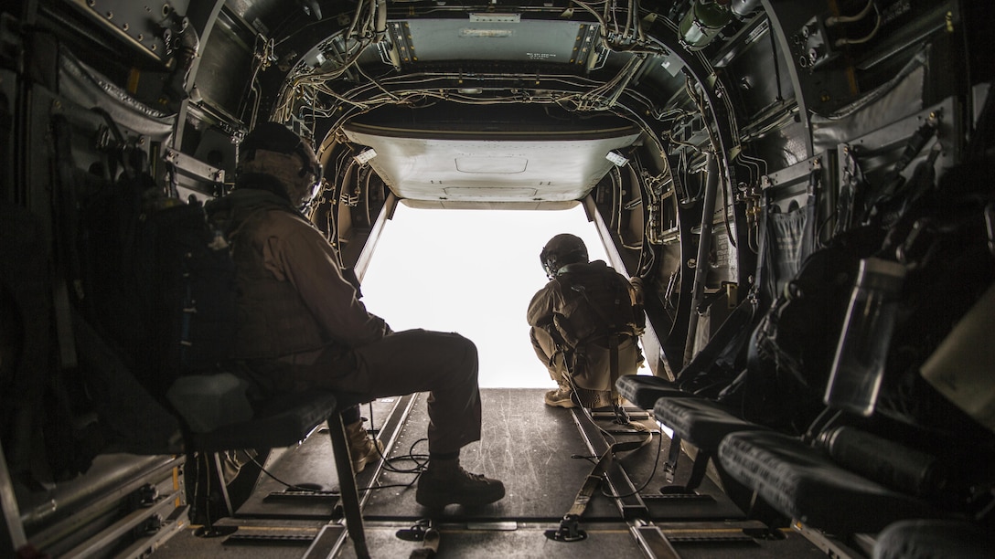 Two crew chiefs with Marine Medium Tiltrotor Squadron 165 observe the area outside an MV-22B Osprey during a flight from Marine Corps Air Station Miramar to Marine Corps Base Camp Pendleton, California, June 8. Crew chiefs worked alongside Osprey pilots in order to maintain visuals for the overall flight.