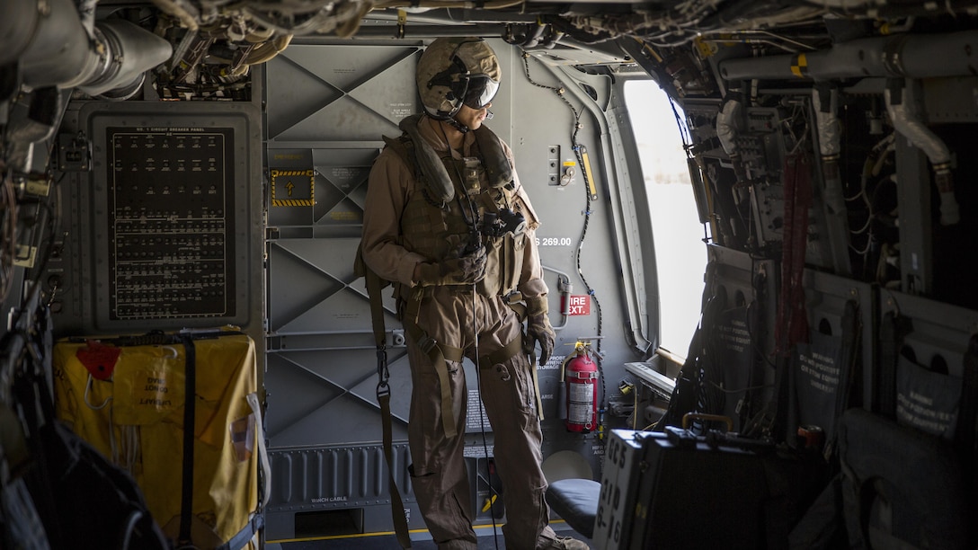 A crew chief with Marine Medium Tiltrotor Squadron 165 looks outside an MV-22B Osprey during a training flight from Marine Corps Air Station Miramar to Marine Corps Base Camp Pendleton, California, June 8. Crew chiefs aboard the Osprey assisted with maintaining visuals during the flight for the pilots.