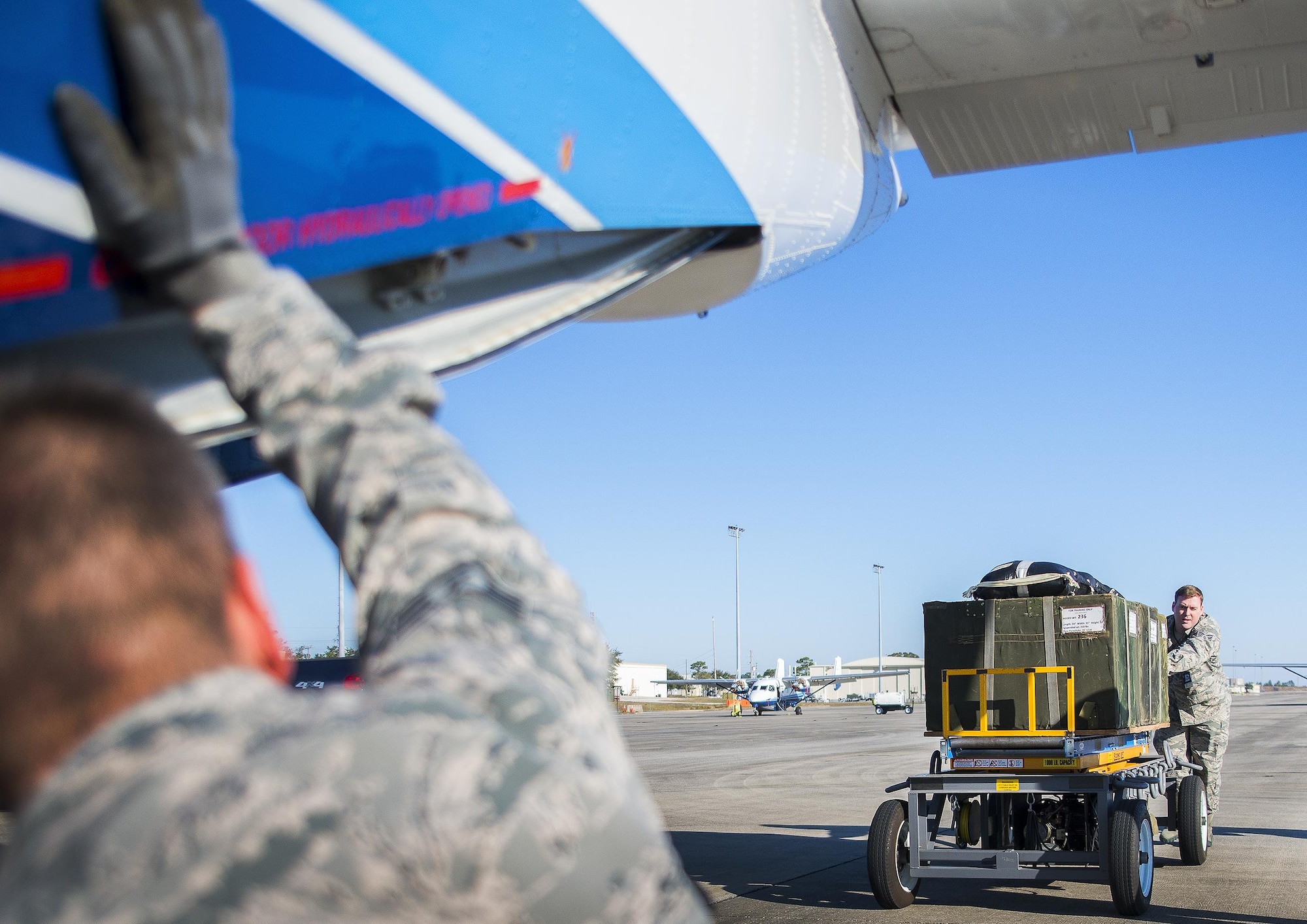 Staff Sgt. Justin Spencer, 919th Special Operations Logistics Readiness Squadron, pushes parachute bundles toward a C-145 Skytruck to be loaded for a training sortie at Duke Field, Fla.  The 300-pound bundles are loaded so new loadmasters can perform their initial airdrop training and prior-qualified Airmen can maintain proficiency.  (U.S. Air Force photo/Tech. Sgt. Sam King)  