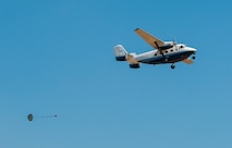 A parachuted sandbag soars out of the back of a C-145 Skytruck during an airdrop mission over the Eglin Air Force Base range.  New and prior-qualified loadmasters release sandbags and 300-pound boxes from the 919th Special Operations Wing aircraft to as part of their initial airdrop or proficiency training.  The 919th Special Operations Logistics Readiness Squadron’s Airmen are responsible for packing, securing and recovering the equipment and parachutes.  (U.S. Air Force photo/Tech. Sgt. Sam King)  