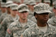 Diverse group of Soldiers wearing ACU's standing in formation outside during the day.
