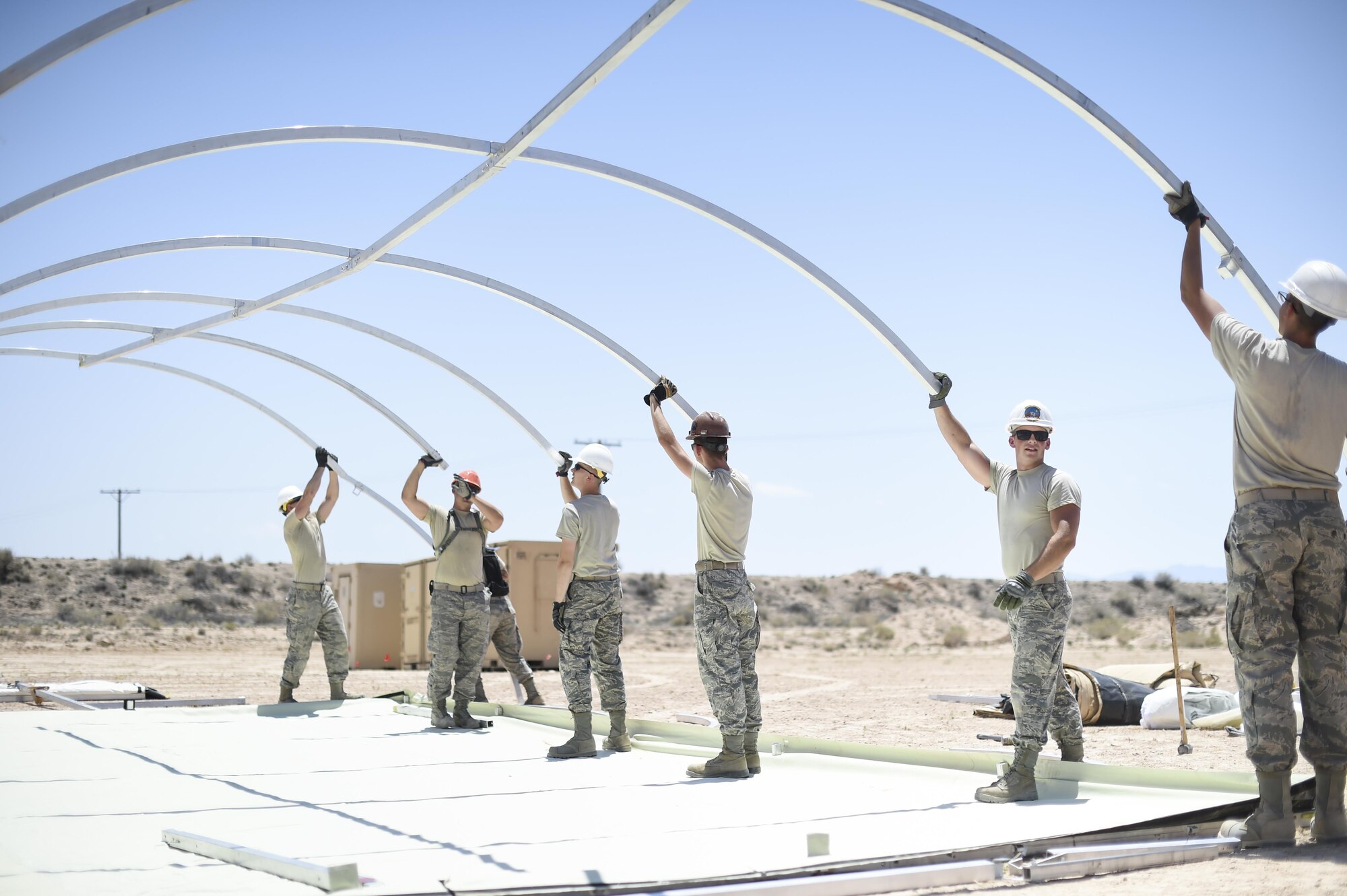 Airmen from the 49th Materiel Maintenance Group and the 49th Civil Engineer Squadron work together to build a structure during a three day joint training exercise at Holloman Air Base, N.M on June 7. The Base Expeditionary Airfield Resources team is comprised of several Air Force specialties including aerospace ground equipment, structures, heating/air conditioning and electrical, as well as lodging, industrial and airfield capabilities at various locations throughout the world. Members of BEAR base build hangars in preparation to deploy at a moments notice. (Last names being withheld due to operational requirements. U.S. Air Force Photo by Staff Sgt. Stacy Moless)