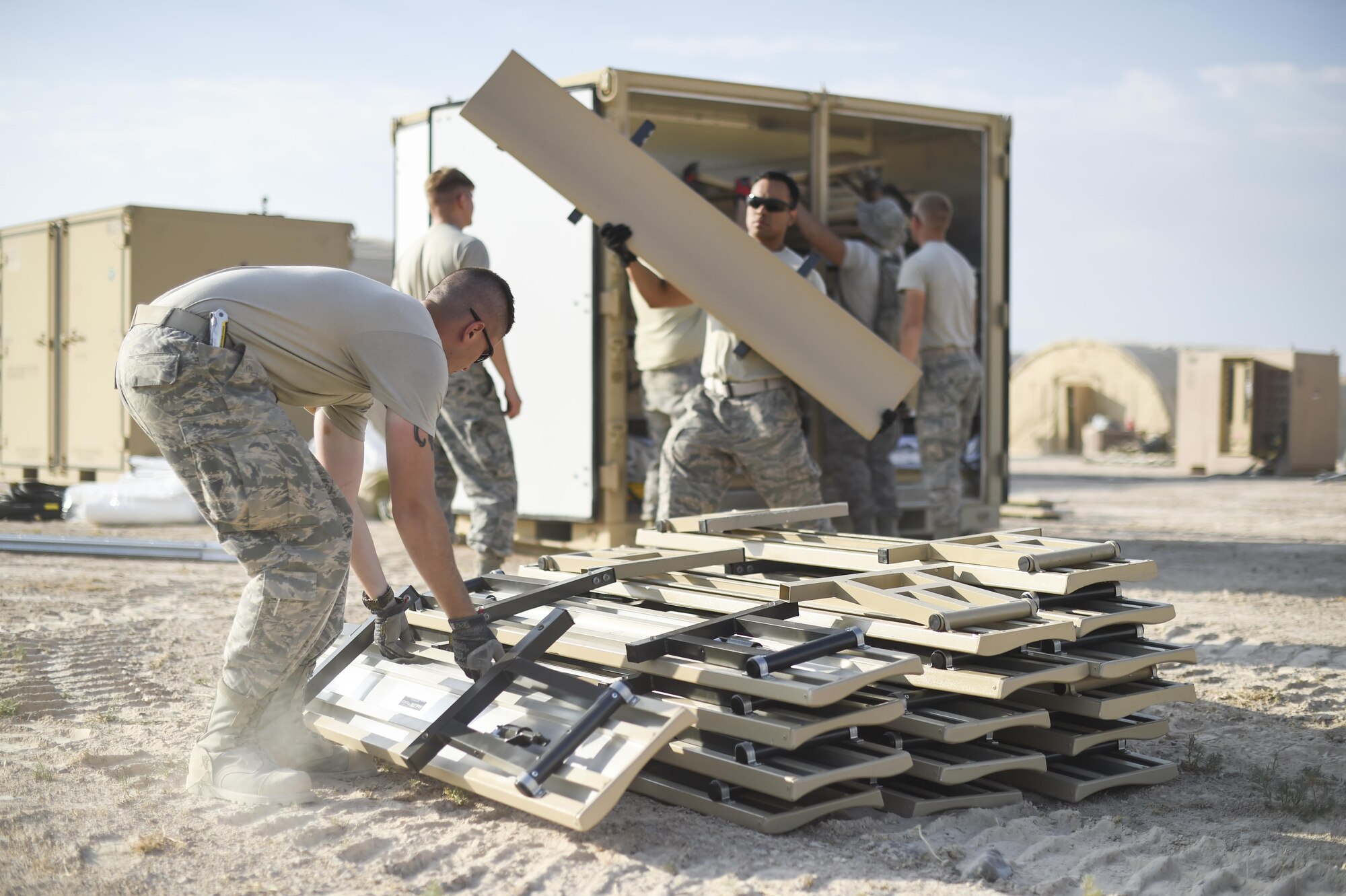 Airmen from the 49th Materiel Maintenance Group and the 49th Civil Engineer Squadron work together to unload benches used for seating inside a dining facility being built during a three day joint training exercise at Holloman Air Base, N.M. on June 7. Airmen from the 49th Materiel Maintenance Group and the 49th Civil Engineer Squadron work together to form the Base Expeditionary Airfield Resources team. The BARE Base team is comprised of several Air Force specialties including aerospace ground equipment, structures, heating/air conditioning and electrical, as well as lodging, industrial and airfield capabilities at various locations throughout the world. Members of BEAR base build hangars in preparation to deploy at a moments notice. (Last names being withheld due to operational requirements. U.S. Air Force Photo by Staff Sgt. Stacy Moless)