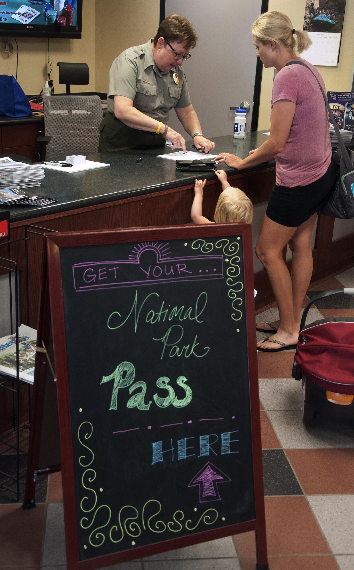 A park ranger from the Grand Teton National Park distributes a National Park Military Pass for an Airman June 8, 2016, during the Outdoor Recreation grand re-opening in the Fall Hall Commons on F.E. Warren Air Force Base, Wyo. The rangers were a welcome addition to the open house, as Outdoor Rec. hosts a number of trips each year that visit national parks in the area. (U.S. Air Force photo by Senior Airman Brandon Valle)