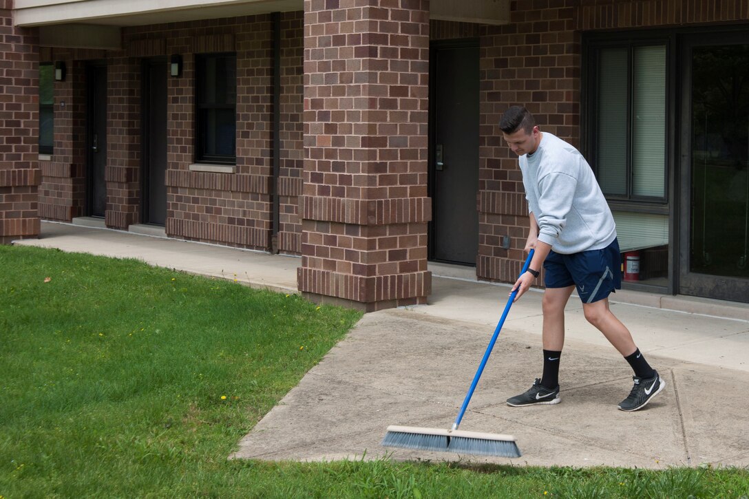 Airman 1st Class Jacob Pounds, 11th Force Support Squadron outbound assignments counselor, sweeps the walkway of building 1657 at Joint Base Andrews, Md., June 3, 2016.  Pounds is assigned to bay orderly, a base-wide program that helps maintains the grounds and common areas of the dorms. (U.S. Air Force photo by Airman 1st Class Rustie Kramer/Released
