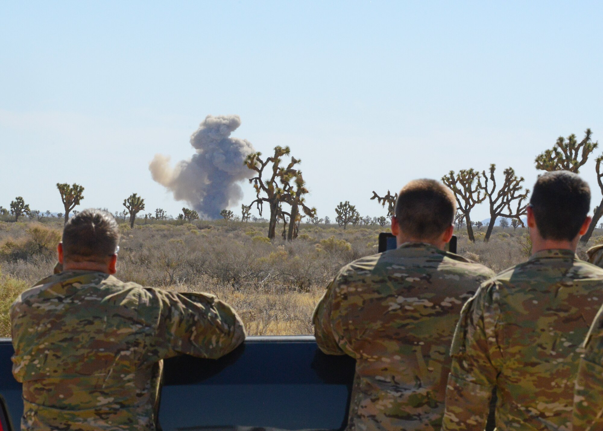 Aimen from the 812th Civil Engineering Squadron, Explosive Ordnance Disposal, watch as 15 gallons of nitrocellulose-dope lacquer is blown up at a range on Edwards Air Force Base June 6. EOD assisted the City of Lancaster with the disposal. The hazardous chemical was found at a waste facility in Lancaster and is highly volatile. (U.S. Air Force photo by Kenji Thuloweit) 