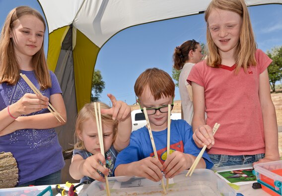 From the left, Emma, Lily, Ethan, and Nicole Moultrie use chopsticks to experience what some birds must do to pick up and eat food. The Moultries had this and other experiences during the “Kickin’ it…for Conservation!” energy and environmental fair held at Hill Air Force Base, Utah, June 9. (U.S. Air Force photo by Paul Holcomb)