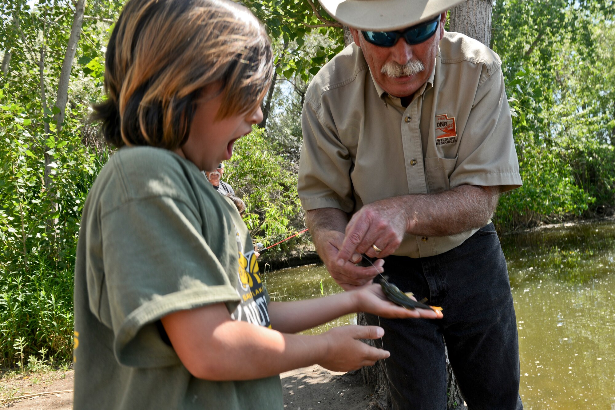 Maribel Martinez, daughter of Staff Sgt. Joseph Martinez, reacts as she receives a fish which she caught during a catch and release event at Hill Air Force Base, June 9. Phil Douglass, Utah Dept. of Wildlife Resources outreach manger, assisted with the catch. Martinez and Douglass were on base to participate in “Kickin’ it…for Conservation!” activities, an energy and environmental fair held at the base’s Pond 3, or “Duck Pond.” (U.S. Air Force photo by Paul Holcomb)