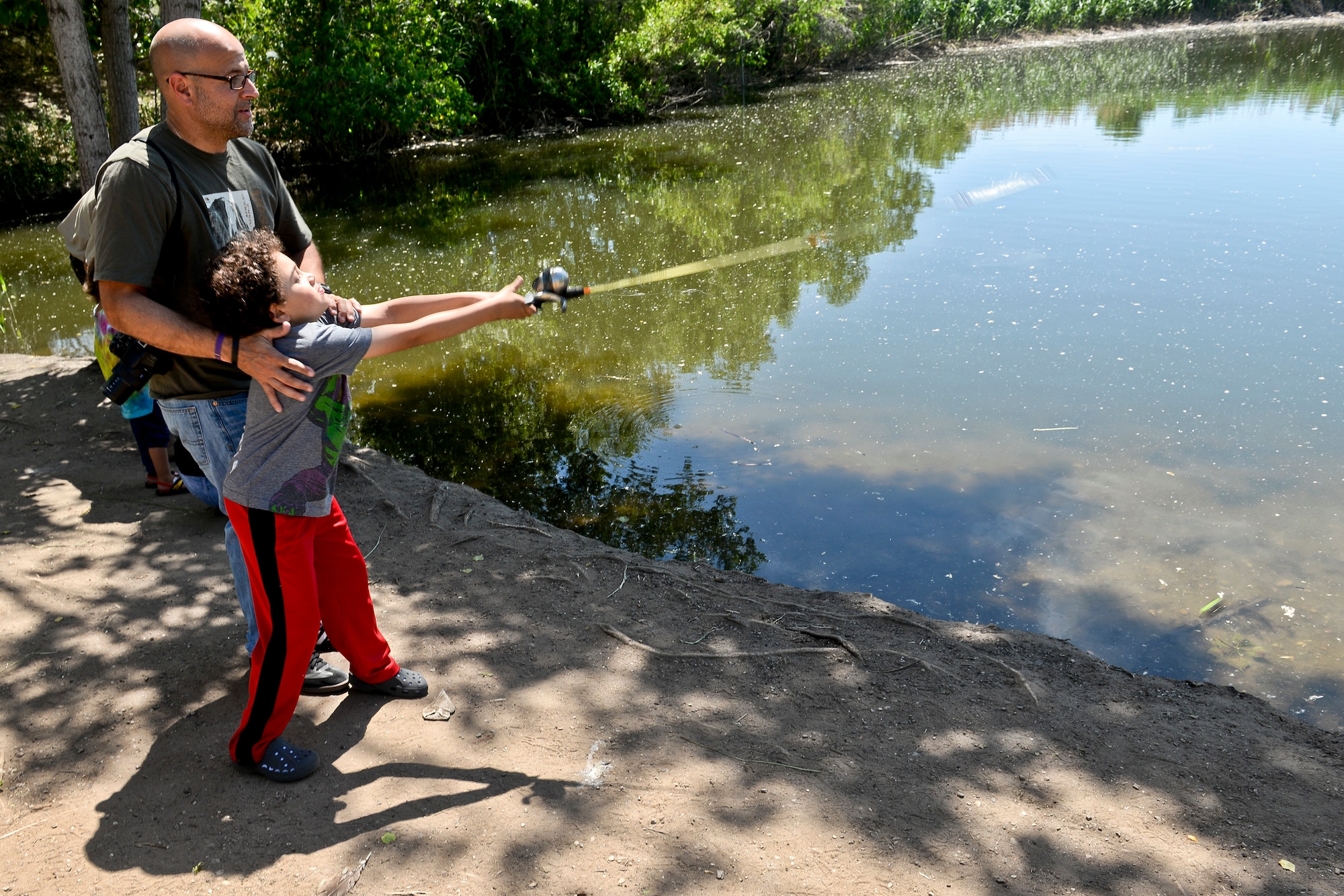 Nolan Fenimore, with the help of his father Billy, casts a line June 9 at Pond 3 on Hill Air Force Base. The Fenmiores visited the base to participate in “Kickin’ it…for Conservation!” activities, which included catch and release fishing, crafts, bird house building, and wildlife resources. (U.S. Air Force photo by Paul Holcomb)