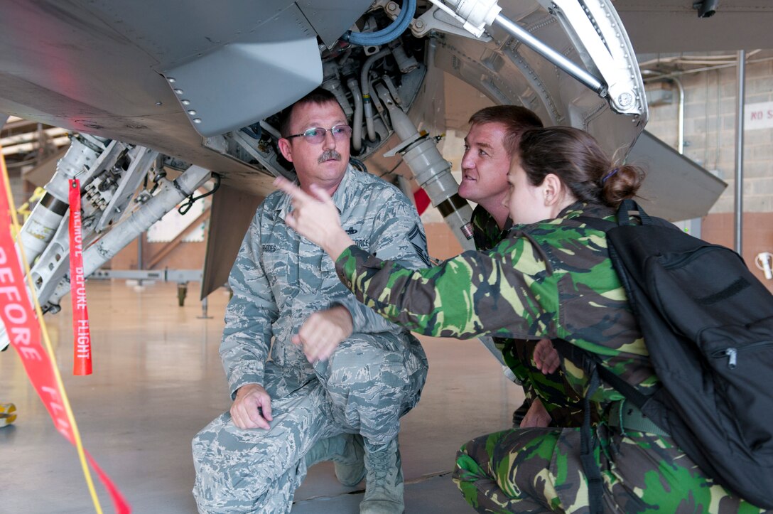 Romanian air force 2nd Lt. Chirila Sandu, right, and Romanian air force Maj. Constantin Pecete talk with U.S. Air Force Senior Master Sgt. William Rhodes, avionics element superintendent with the 187th Maintenance Squadron, about a U.S. Air National Guard F-16 Fighting Falcon aircraft June 8, 2016, in the hangar at the Montgomery Regional ANGB, Ala. Romanian air force maintainers visited the 187th to share information and strengthen their partnership. (U.S. Air National Guard photo by Staff Sgt. Jared Rand/Released)