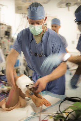 Lt. Col Chance Henderson, 455th Expeditionary Medical Group orthopedic surgeon, wraps gauze around the patients legs after surgery, June 10, 2016, at Craig-Joint Theater Hospital, Bagram Airfield, Afghanistan. Lt. Col. Henderson has performed multiple surgeries on the patient in an effort to save her leg from amputation. The patient was brought to the hospital after suffering from a gun-shot wound. (U.S. Air Force photo by Tech. Sgt. Tyrona Lawson)