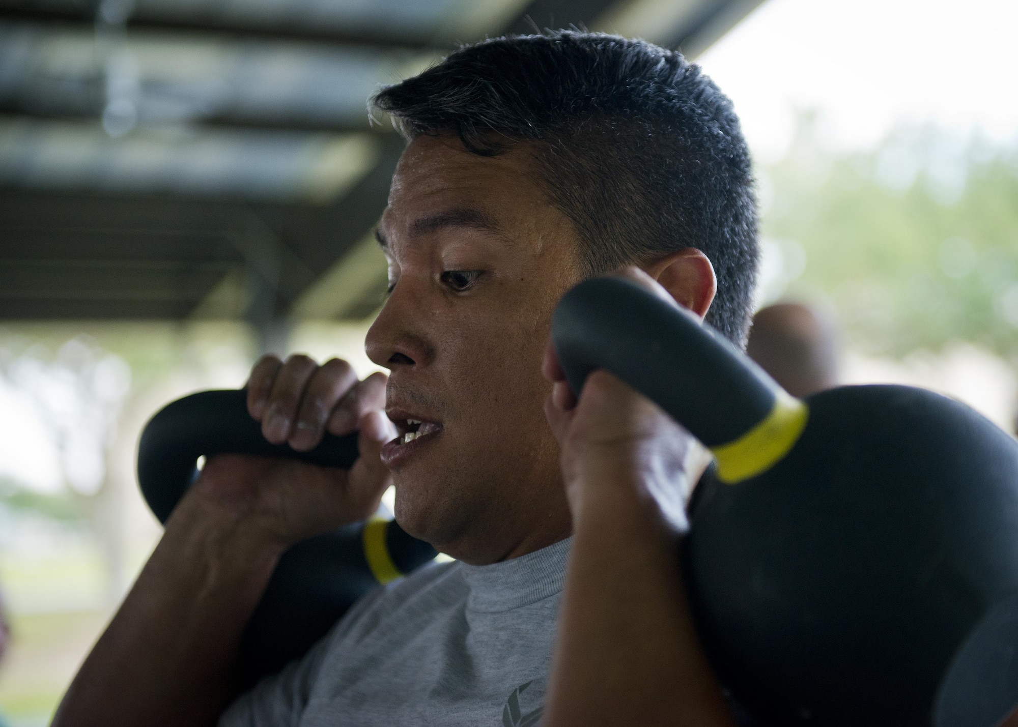 Tech. Sgt. Teddy Batarao, 919th Special Operations Communications Squadron, prepares to lift two kettlebells over his head during a team combat fit competition June 11 at Duke Field, Fla.  The three-round competition pushed the teams to their limits with repetitive weight lifting, rowing, sled-pulling and other kinetic activities.  (U.S. Air Force photo/Tech. Sgt. Sam King)