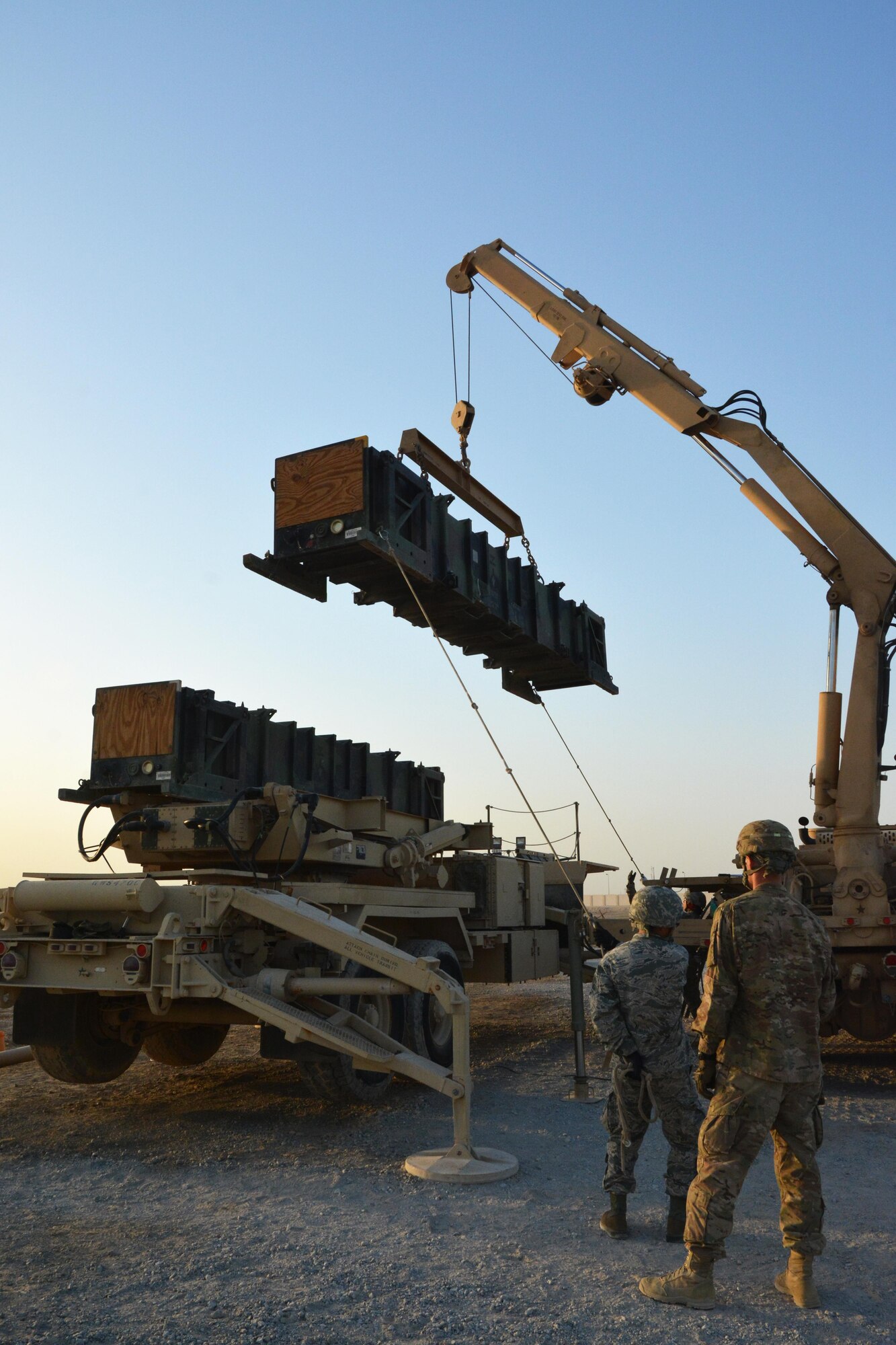 A Soldier from the Army 3rd Battalion 2nd Air Defense Artillery Regiment watches as a 380th Expeditionary Aircraft Maintenance Squadron Airman steadies a Patriot training missile during the load of a launcher, June 4. Airmen were given an opportunity to load a launcher in an information exchange between the Army and Air Force to augment understanding of how the services work together to maintain air superiority. (U.S. Air Force photo by Staff Sgt. Samantha Mathison)