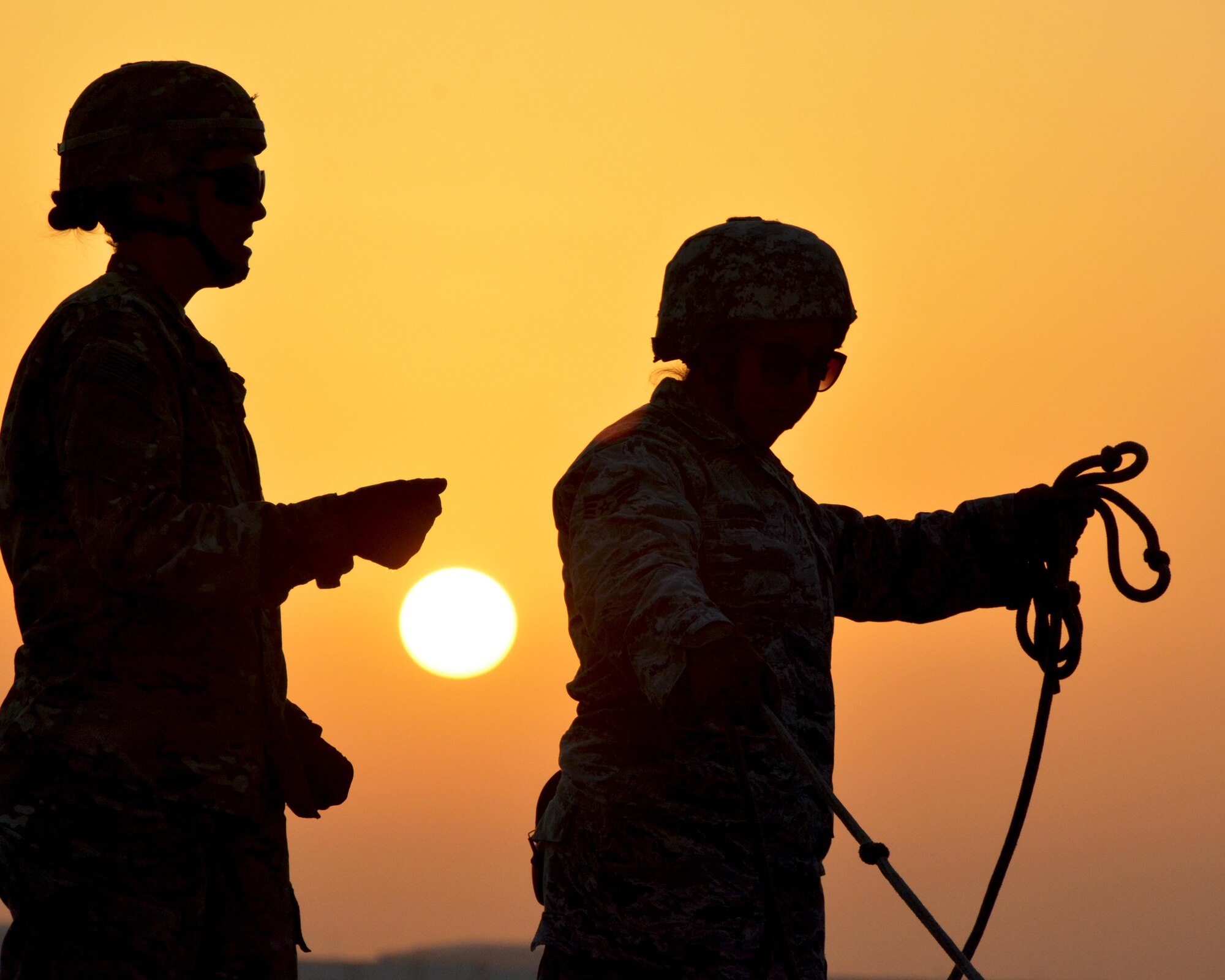Spc. Brittany, Army 3rd Battalion 2nd Air Defense Artillery Regiment Charlie Battery missile technician (left), explains how to hold guide ropes to Senior Airman Karen, 380th Expeditionary Aircraft Maintenance Squadron munitions load crewmember (right), during a Patriot training missile load, June 4. The Army Soldiers invited Airmen to the Patriot site in an information exchange aimed at enhancing understanding of each service’s role in air superiority. (U.S. Air Force photo by Staff Sgt. Samantha Mathison)
