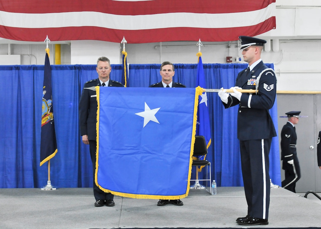Maj. Gen. Anthony German (left), the Adjutant General of the State of New York and Brig. Gen. Greg Semmel (right) stand for the unfurling of the brigadier general flag, during his promotion ceremony held on Hancock Field in Syracuse, NY Friday, June 10. Semmel will now serve as Assistant Adjutant General – Air for the New York Air National Guard. (U.S. Air National Guard photo by Tech. Sgt. Jeremy M. Call/Released)