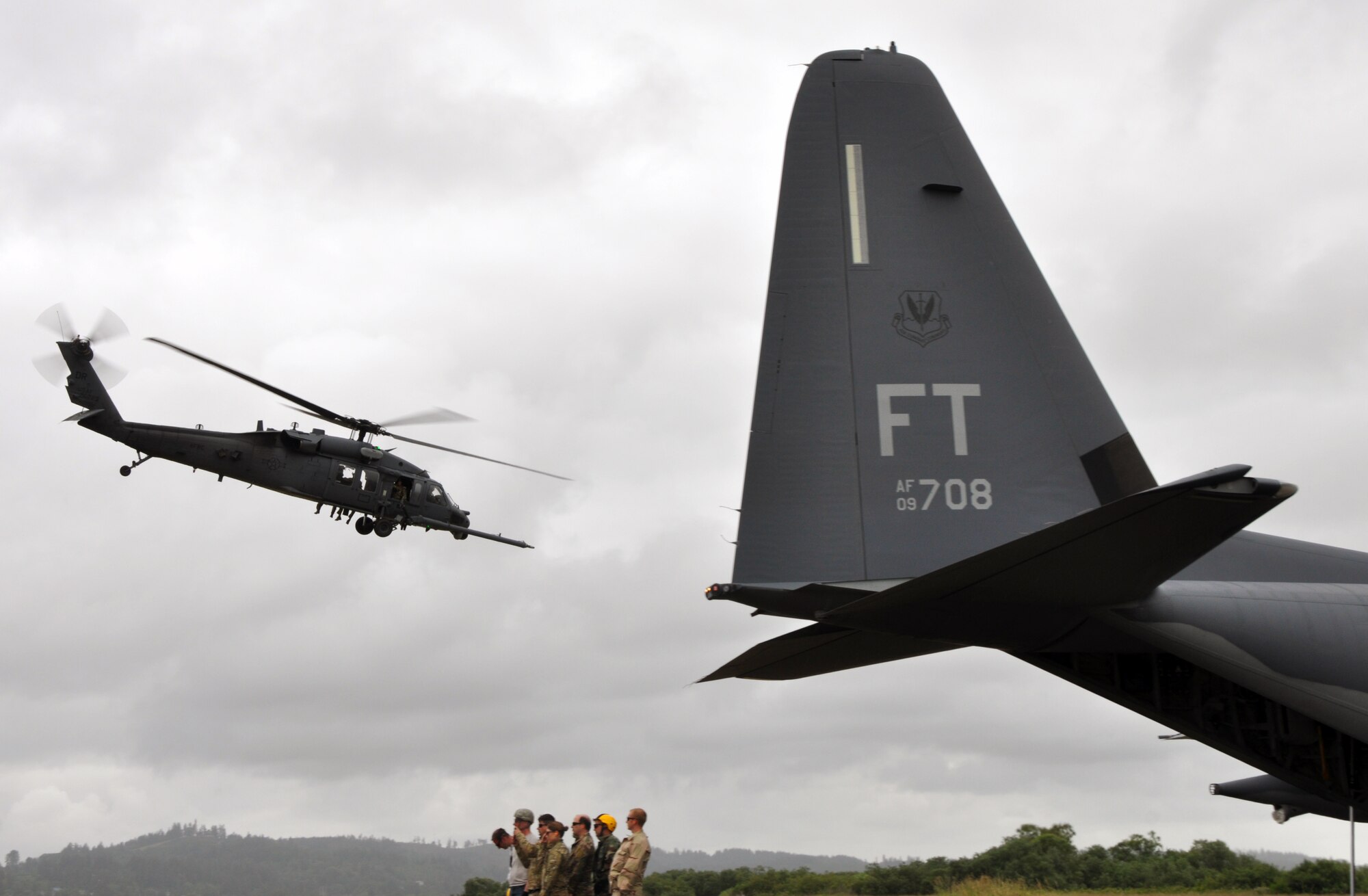 Reservists from the 304th Rescue Squadron, Portland Air National Guard Base, Ore., stand behind an HC-130 as they watch an HH-60G Pave Hawk helicopter from the 305th Rescue Squadron, Davis-Monthan Air Force Base, Ariz., depart the airport in Astoria, Ore., June 8, 2016. Several 304th personnel, plus Air and Army National Guardsmen and other local, state and federal government and civilian organizations participated in Cascadia Rising, a disaster response exercise simulating a magnitude 9.0 earthquake and subsequent tsunami in the Pacific Northwest. (U.S. Air Force photo by 1st Lt. Anna-Marie Wyant)