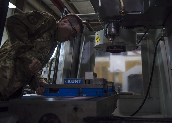 Staff Sgt. Tyler Duke, 455th Expeditionary Maintenance Squadron metals technician, tightens a clamp on a computer numerical control mill, June 09, 2016, Bagram Airfield, Afghanistan. The CNC machine can create complex aircraft components from raw metal that would normally be impossible to make conventionally. (U.S. Air Force photo by Senior Airman Justyn M. Freeman)