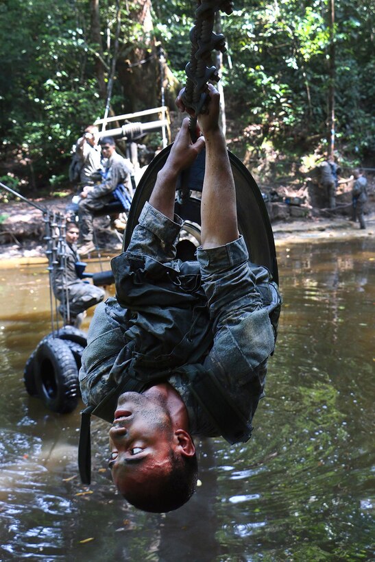 A soldier pulls himself out of a hanging barrel obstacle at the French jungle warfare school in Gabon, June 9, 2016. Army photo by Staff Sgt. Candace Mundt