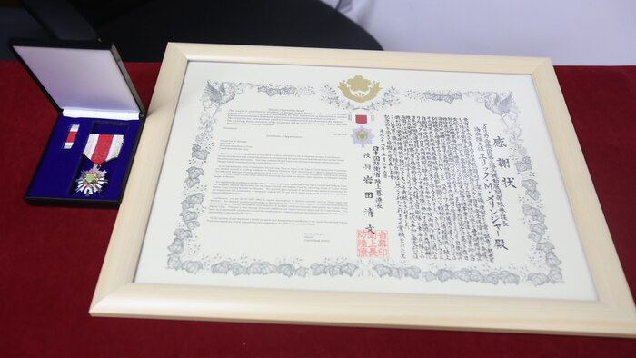 An award ceremony was held June 13, 2016, at Camp Courtney, Okinawa, Japan. U.S. Marine Col. Eric M. Mellinger received an award from Japanese Ground Self-Defense Force Col. Shusei Hotta for significantly contributing to increasing training opportunities for the JGSDF by advancing co-use of Marine Corps training facilities on Okinawa and expanding III Marine Expeditionary Force efforts to participate in alliance/bilateral exercises. Hotta, the deputy chief of Policy and Programs Division, Ground Staff Office, JGSDF, presented the award on behalf of Gen. Kiyofumi Iwata, the JGSDF chief of staff. Mellinger is the III MEF chief of staff.