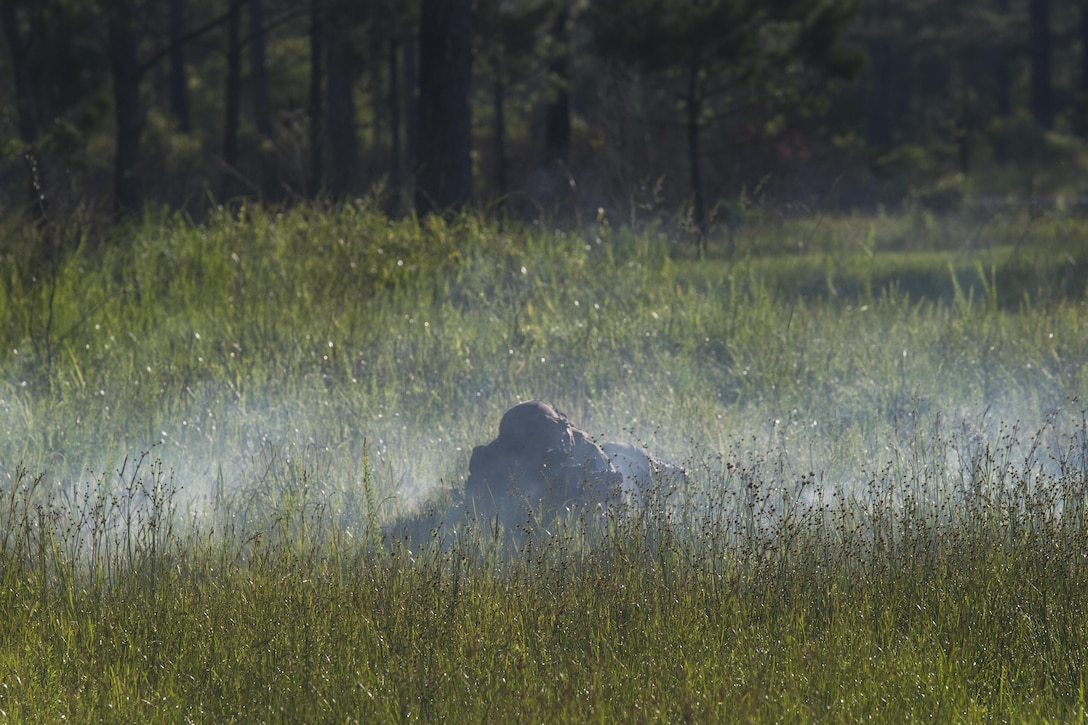 A Marine with 3rd Battalion, 6th Marine Regiment lays in the cover of smoke from a simulation artillery round during the battalions Marine Corps Combat Readiness Evaluation, at Camp Lejeune, N.C.,  June 10, 2016. The MCCRE, a pre deployment exercise, tests the Marines on operational readiness and their ability to operate as a whole.