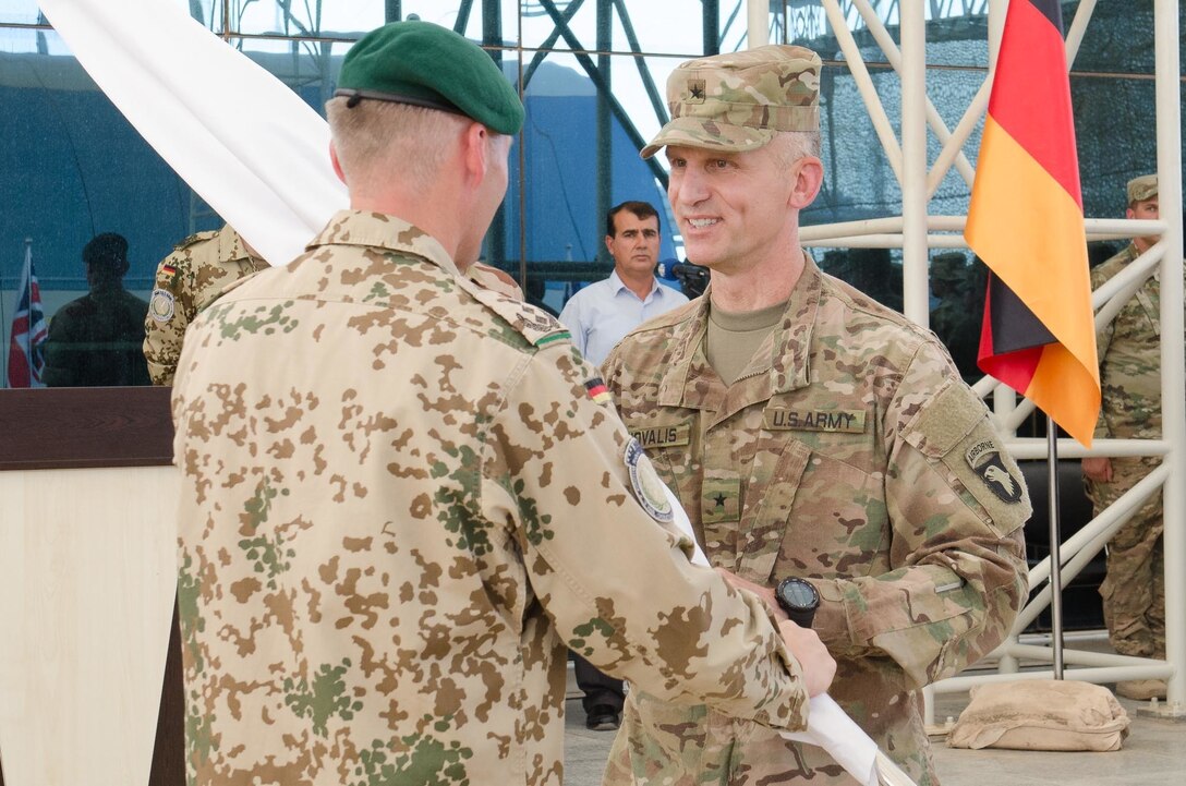 German Col. Bernd Erwin Prill, left, the outgoing commander of the Kurdistan Training Coordination Center, passes the KTCC guidon to U.S. Army Brig. Gen. John Novalis, right, the deputy commanding general for support for the Combined Joint Forces Land Component Command – Operation Inherent Resolve, during a change of command ceremony held near Erbil, Iraq, June 8, 2016. The passing of the guidon between them symbolizes the German coalition partners relinquishing command of the KTCC. The KTCC is one of four Combined Joint Task Force – Operation Inherent Resolve building partner capacity locations dedicated to training Iraqi Security Forces. (U.S. Army Photo by Staff Sgt. Peter J. Berardi/Released)