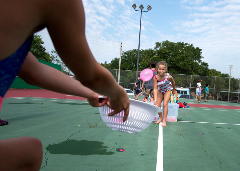 A child from Moody’s Youth Programs tosses a water balloon during Olympic Day, June 10, 2016, at Moody Air Force Base, Ga. Children attempted to accurately toss the balloons into the basket without breaking them. (U.S. Air Force photo by Airman 1st Class Janiqua P. Robinson/Released)