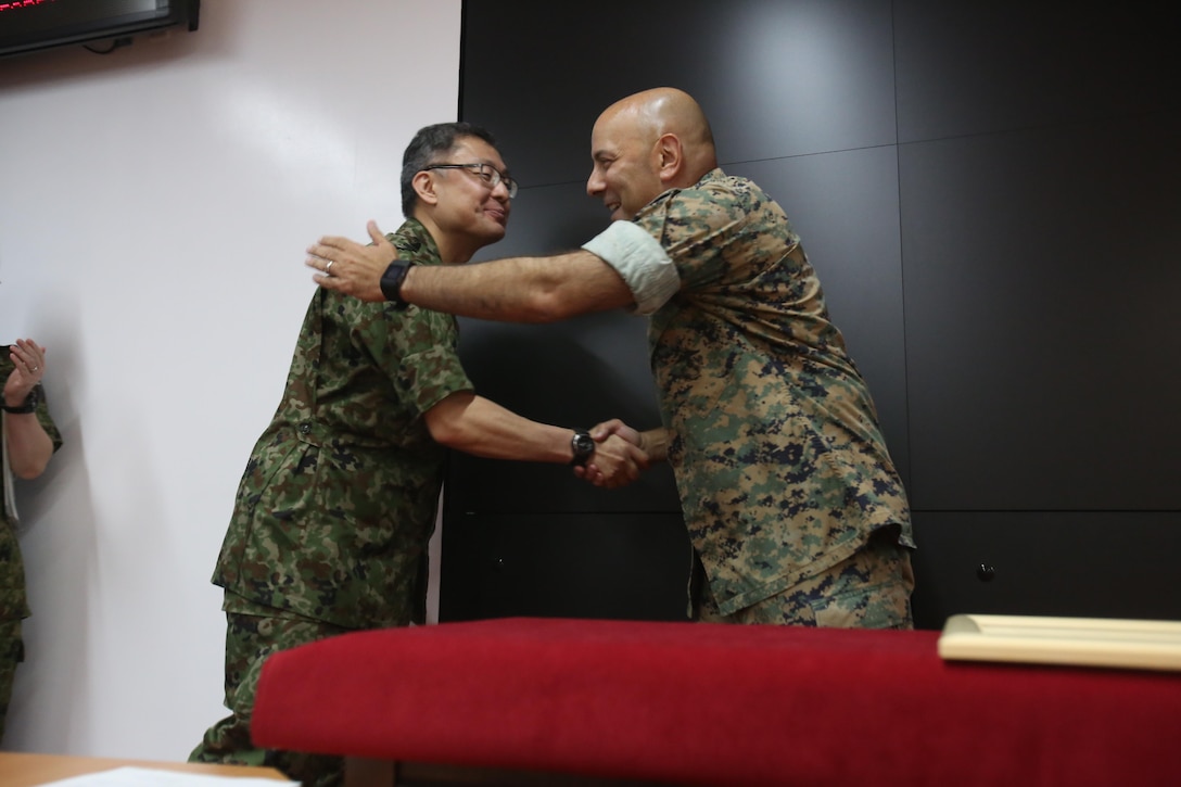 CAMP COURTNEY, Okinawa, Japan, - U.S. Marine Col. Eric M. Mellinger, right, shakes hands with Japanese Ground Self-Defense Force Col. Shusei Hotta, June 13, 2016, at Camp Courtney, Okinawa, Japan. Mellinger received a Defense Cooperation Medal from Gen. Kiyofumi Iwata for significantly contributing to increasing training opportunities for the JGSDF by advancing co-use of Marine Corps training facilities on Okinawa and expanding III Marine Expeditionary Force efforts to participate in alliance/bilateral exercises. Hotta is the deputy chief of Policy and Programs Division, Ground Staff Office, JGSDF. Iwata is  the JGSDF chief of staff. Mellinger is III MEF chief of staff.
