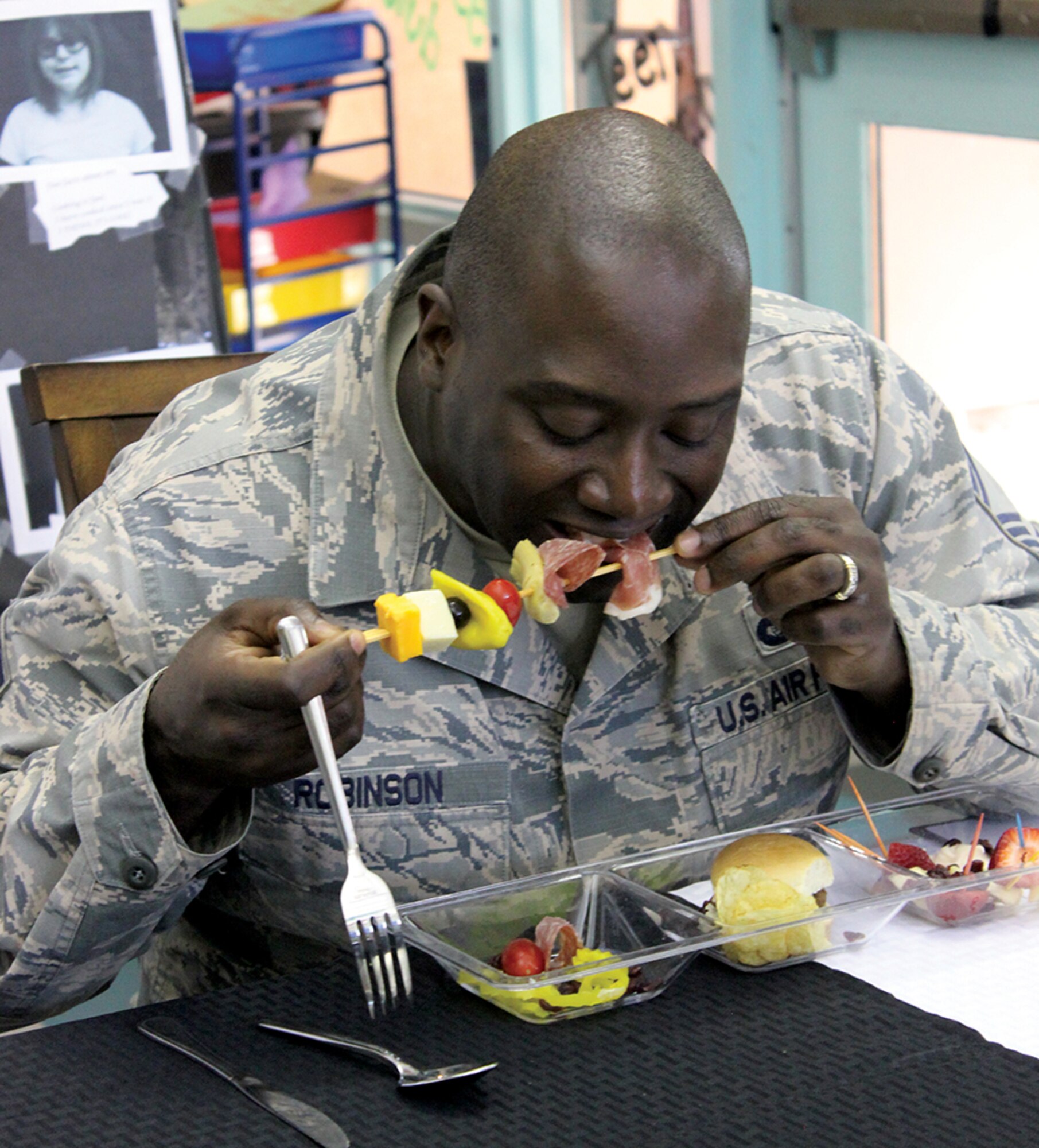 Senior Master Sgt. Robinson of the 377th Force Support Squadron taste the antipasto skewer created by young chefs during the Youth Centers Iron Chef Competition. The challenge is the culminating event for students after 12 weeks learning to cook. (Photo by Bud Cordova)