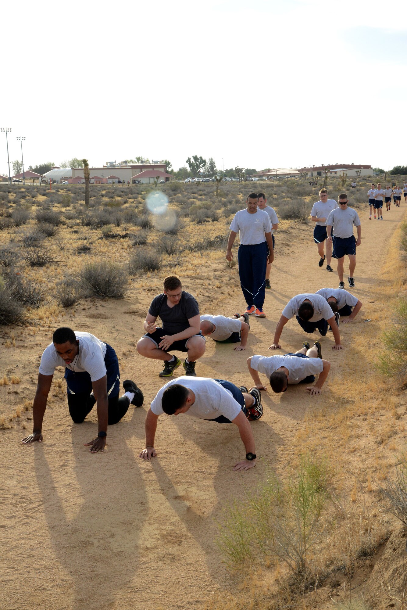 Racers tackle mass pushups during the Fitness Dash at the Rosburg Fitness Center running trail Wednesday. Members were challenged with several cross-fit style challenges during the 1.2-mile running course which includes stretches of loose sand. Organizers asked the participants for feedback after the event, and are looking at making it a quarterly challenge. (U.S. Air Force photo by Christopher Ball.)