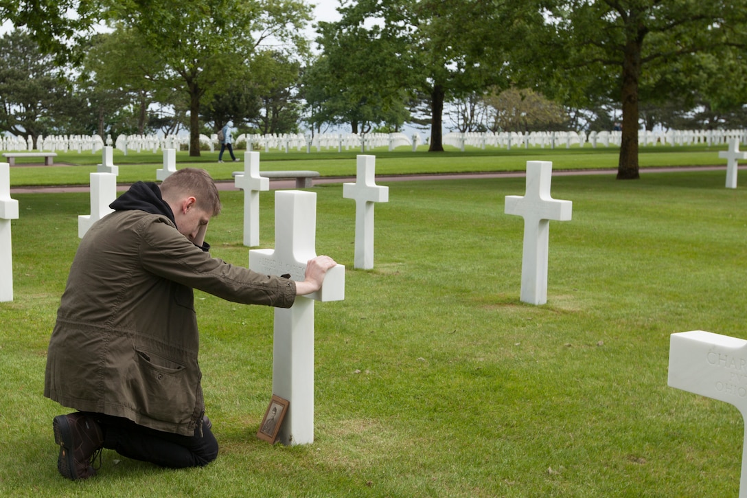 Cpl. Joshua Bettis, an outbound clerk at distribution management office, Henderson Hall, kneels at the grave of his great-great-uncle Army Pfc. Alfred H. Carlton at the Normandy American Cemetery in Colleville sur Mer, France, May 25, 2016. Carlton died from wounds in the D-Day invasion during World War II in Normandy, France. Bettis was the first person in his family to visit the grave. Marine Corps photo by Cpl. Samantha Draughon