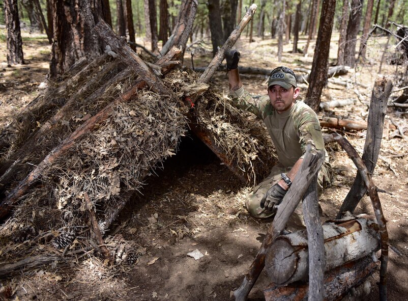 Staff Sgt. Christopher Priddy, member of the the 932nd Airlift Wing explosive ordnance disposal team posses with his completed A-frame shelter, June 1, 2016, Angelus Oaks, California.  It took Priddy roughly 3 hours to gather materials and construct his A-frame shelter. With a small fire and his well constructed shelter, Priddy could be comfortably warm in freezing temperatures  and rain.  (U.S. Air Force photo by Tech. Sgt. Christopher Parr)